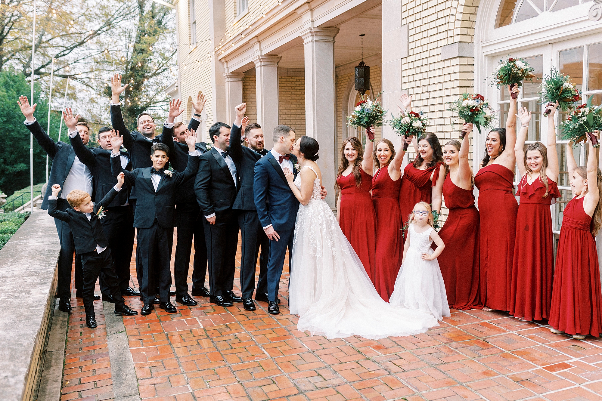 bride and groom kiss surrounded by wedding party cheering