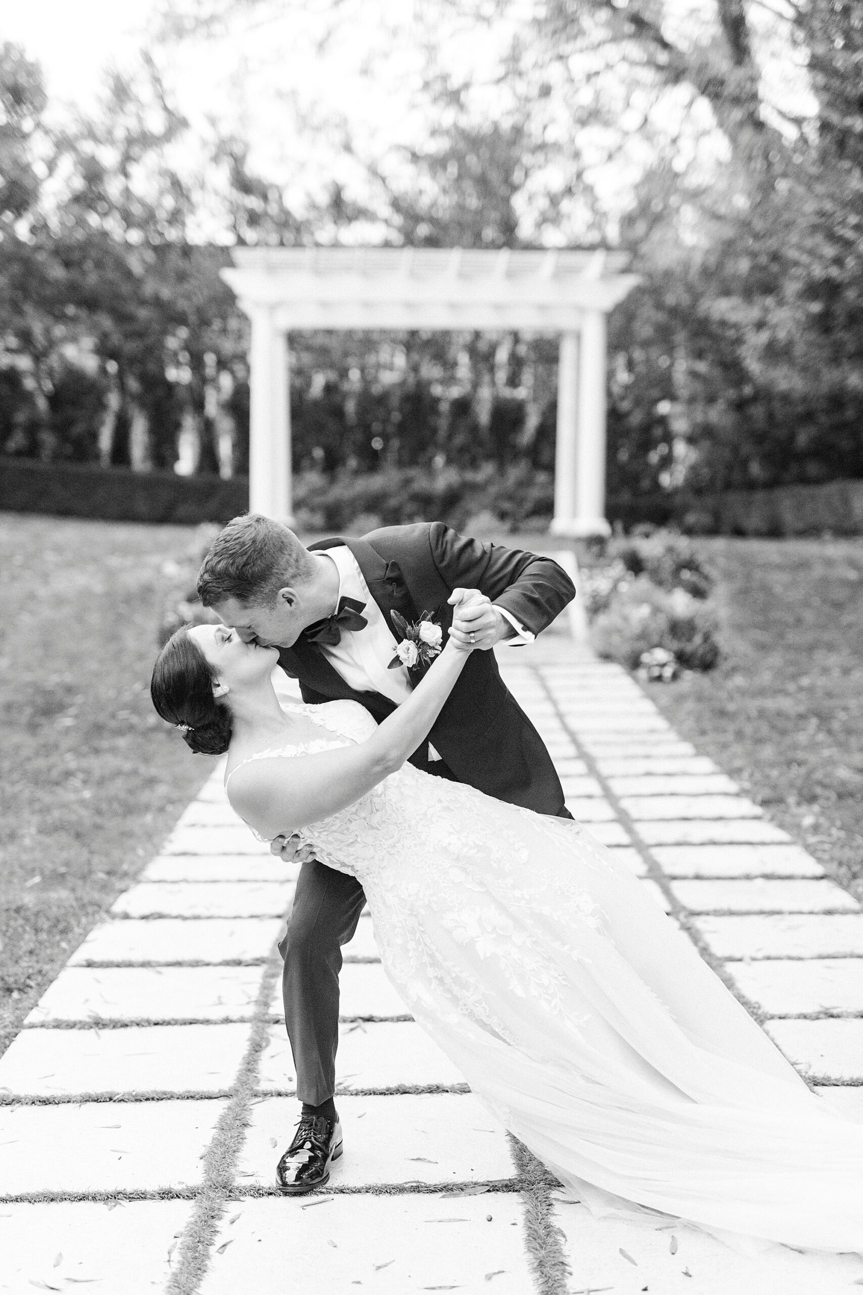 groom kisses bride dipping her in gardens of Separk Mansion