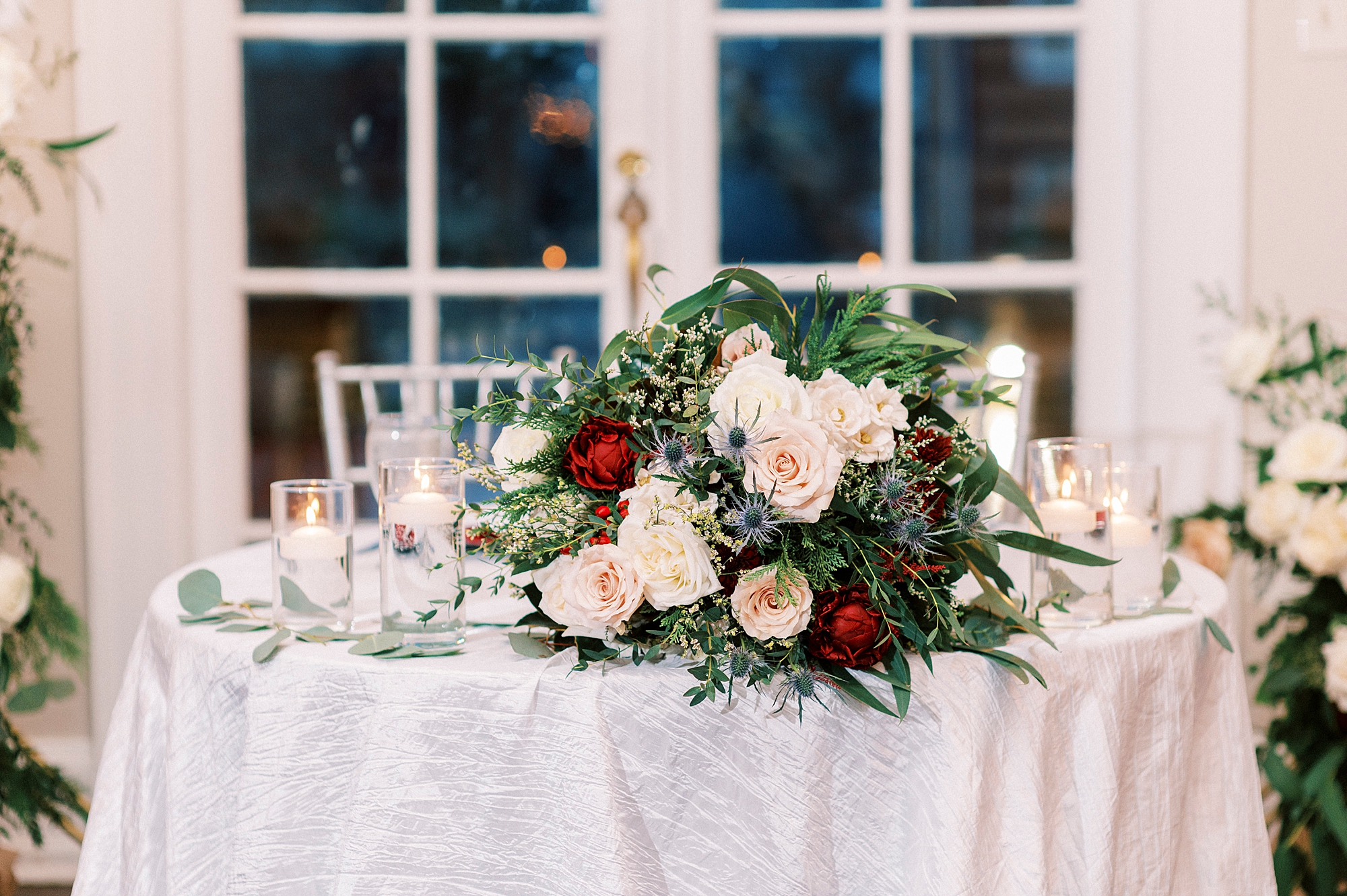 bouquet of red, pink, and white flowers sits on sweetheart table 