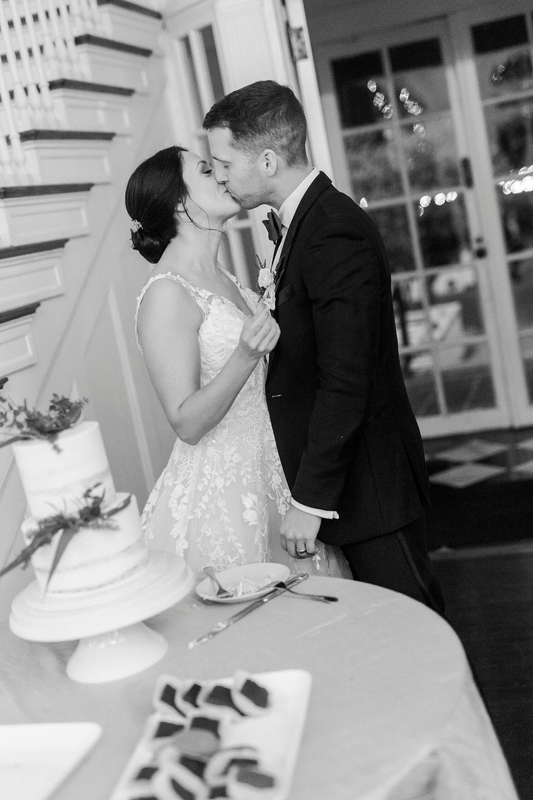 bride and groom kiss after cutting wedding cake during NC wedding reception 