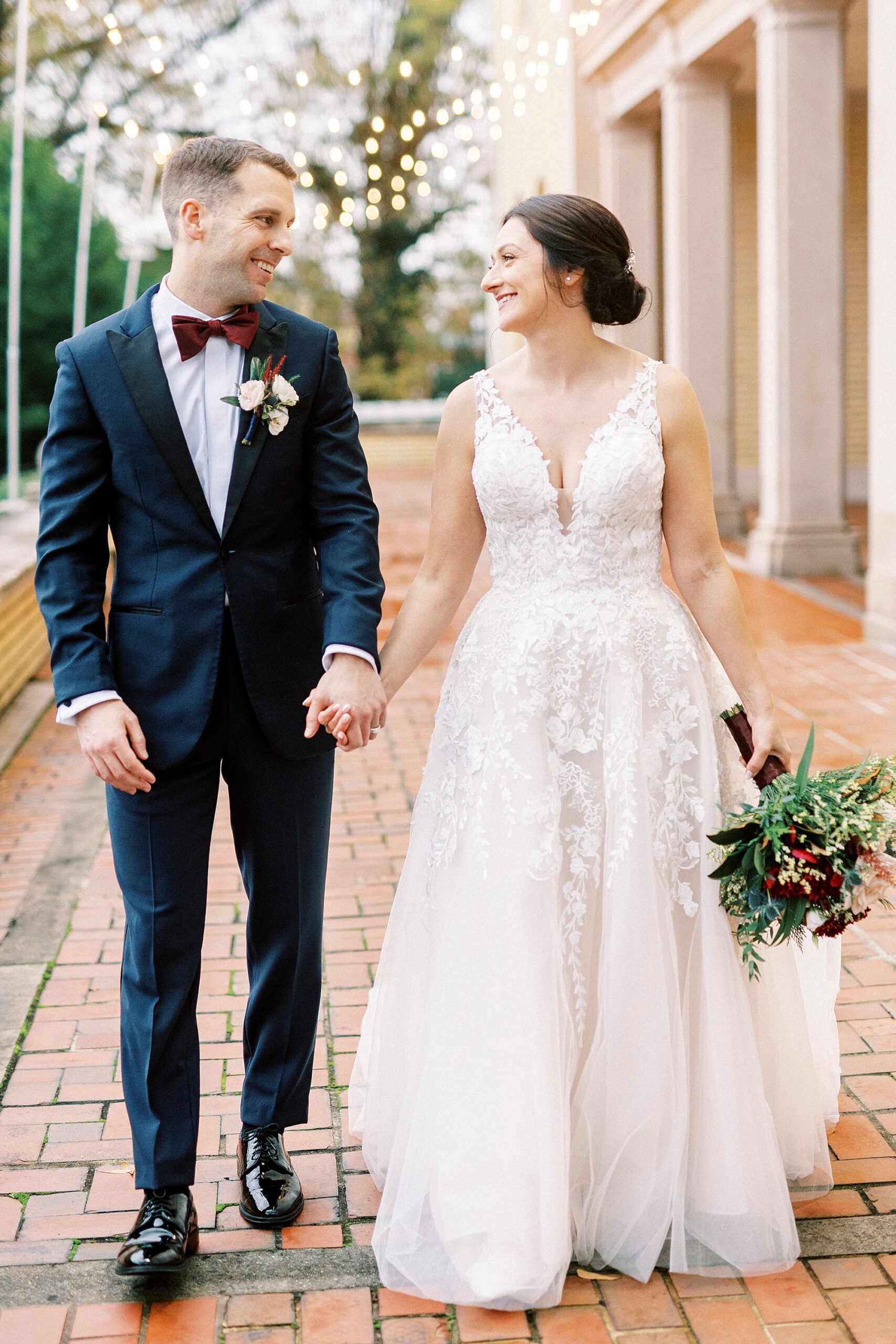 bride and groom hold hands walking on brick patio