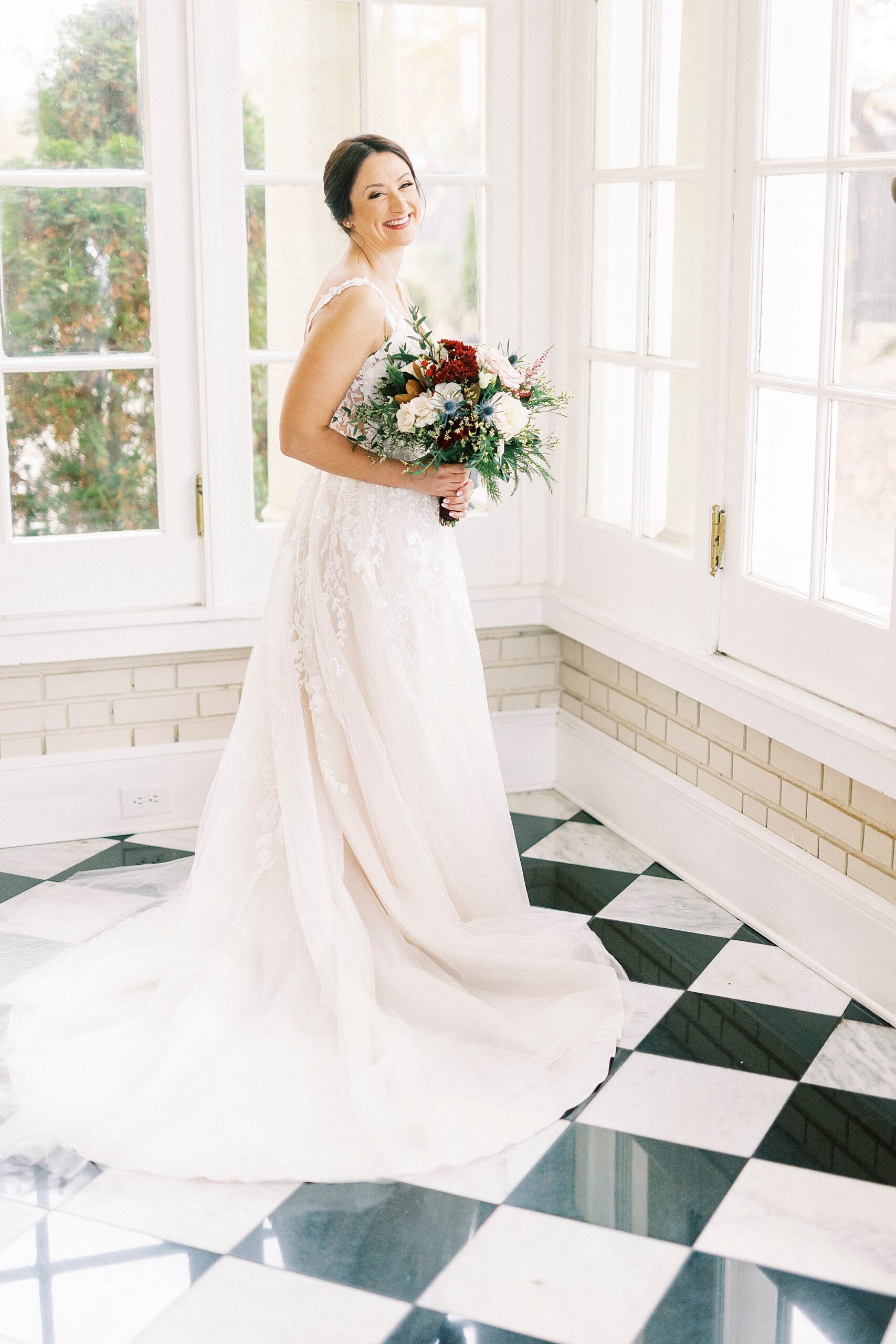 bride stands on black and white floor holding winter bouquet 