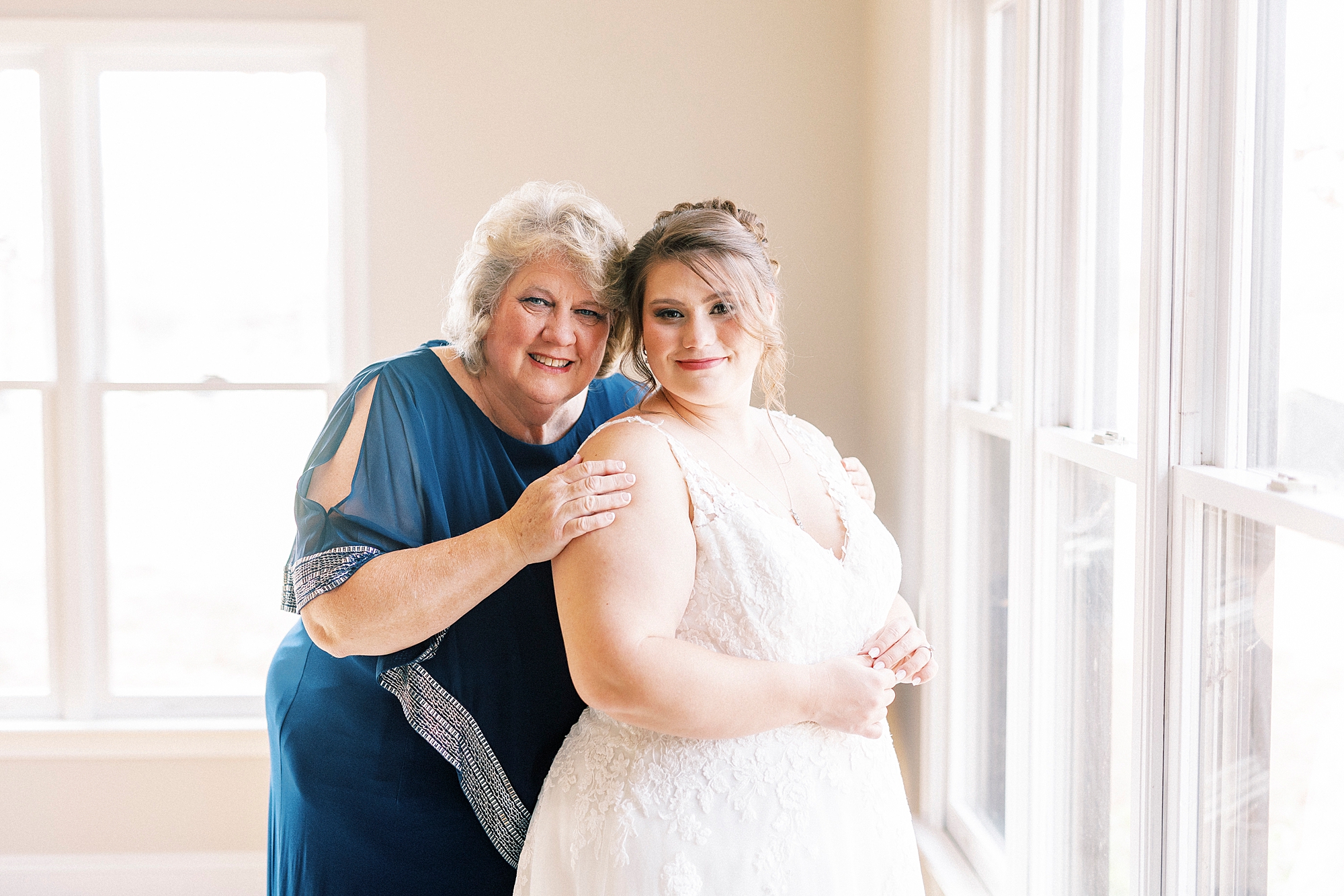 mother in blue dress hugs bride during prep at the Farm at Brusharbor