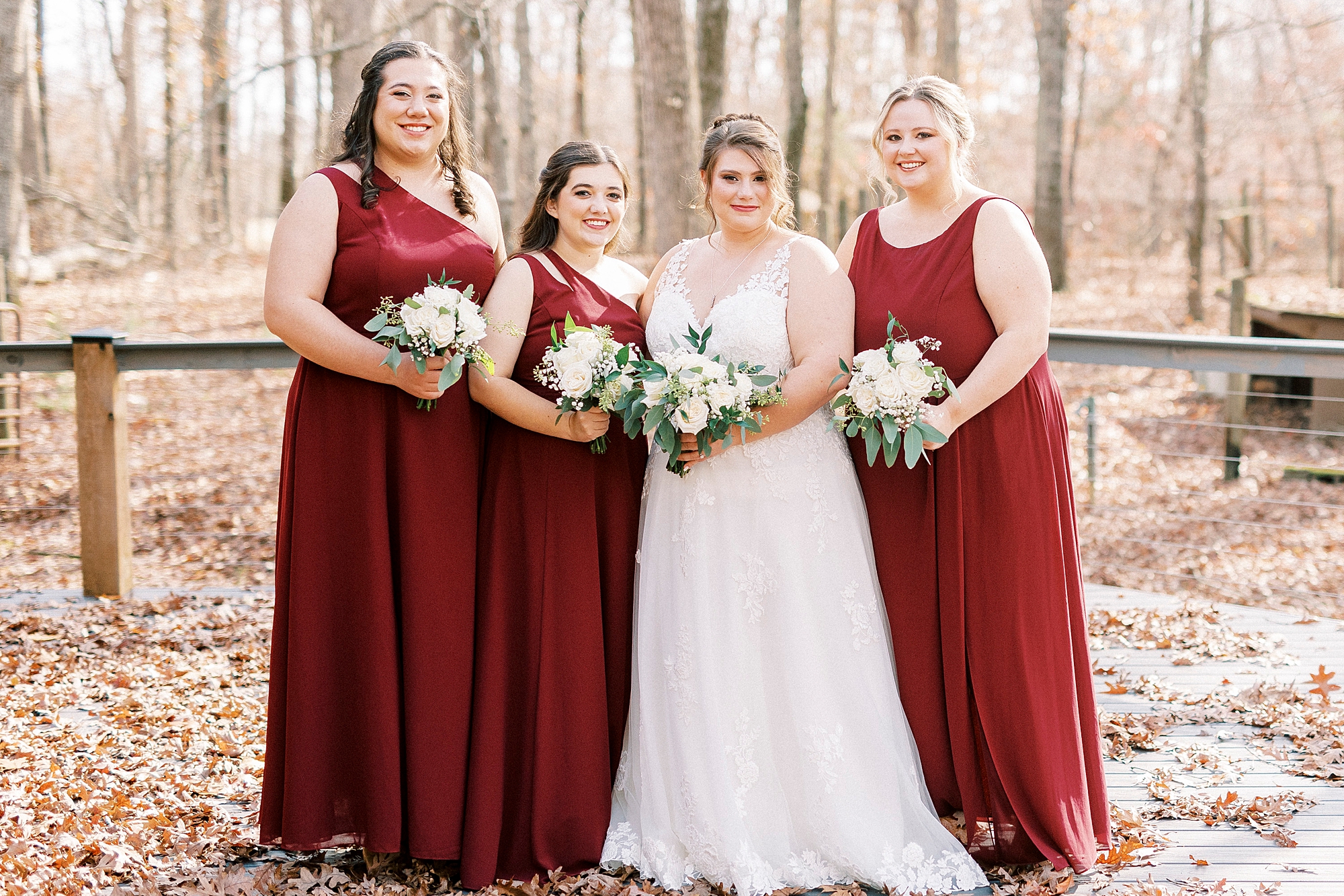 bride poses with bridesmaids in red gowns during fall wedding day at the Farm at Brusharbor