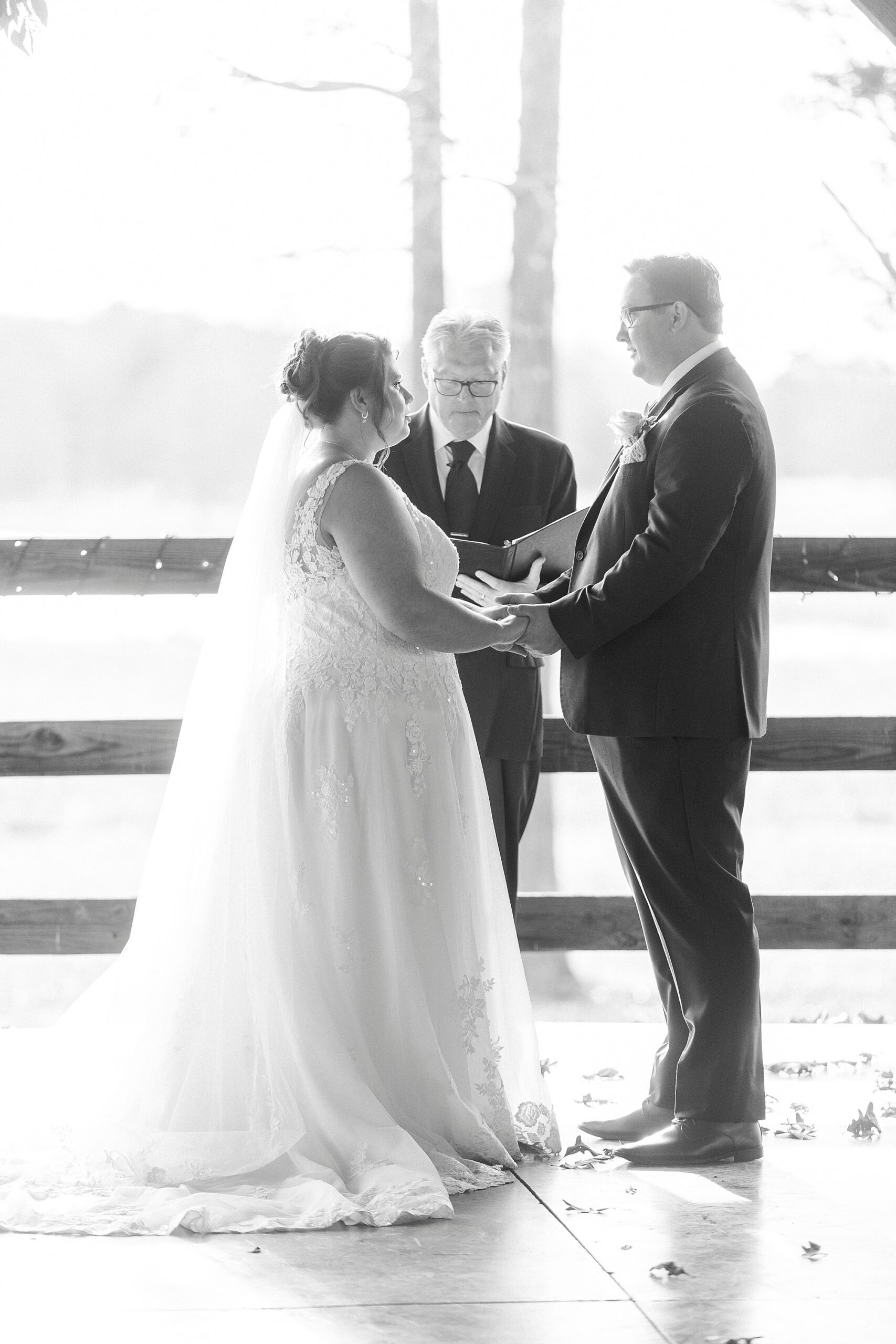 bride and groom hold hands during wedding ceremony at the Farm at Brusharbor pavilion 