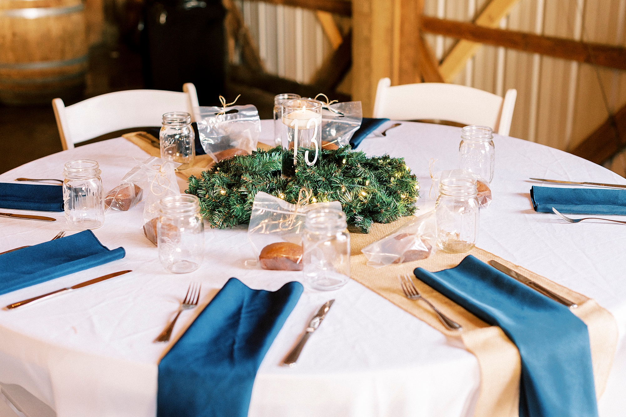 wedding reception place setting with blue napkins and greenery centerpieces at the Farm at Brusharbor