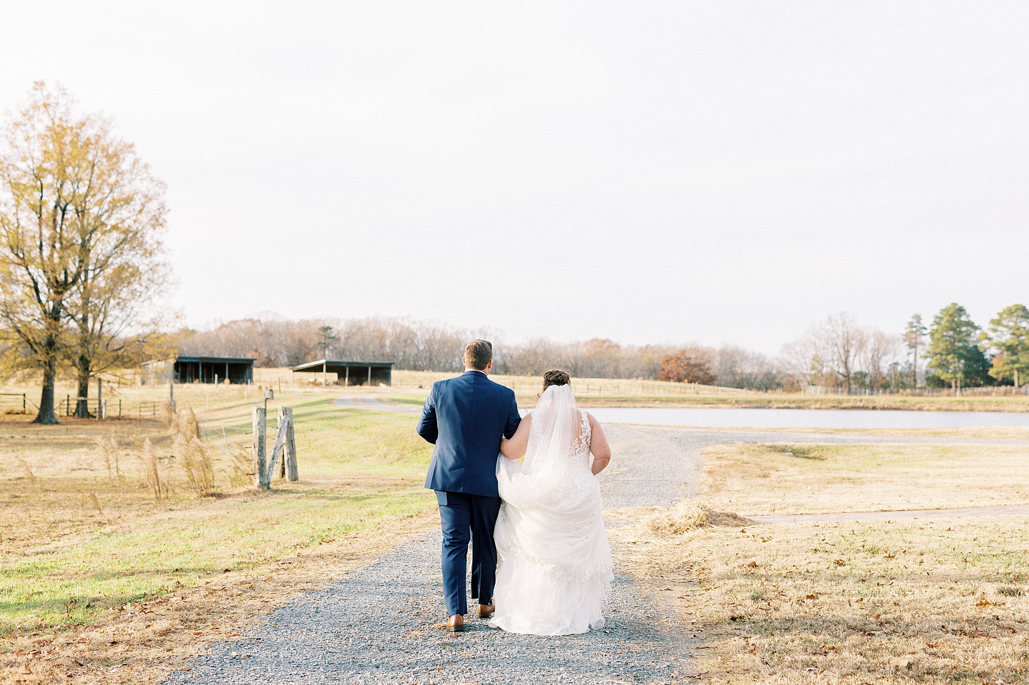 newlyweds hold hands walking down driveway at the Farm at Brusharbor