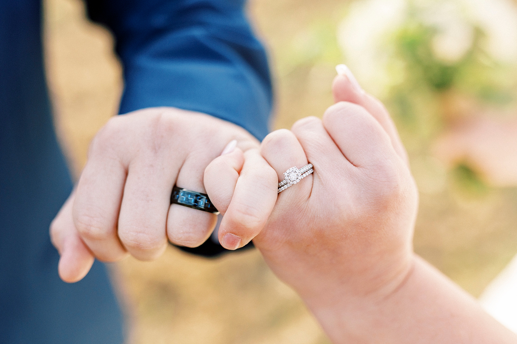 bride and groom link pinkies showing off wedding rings 