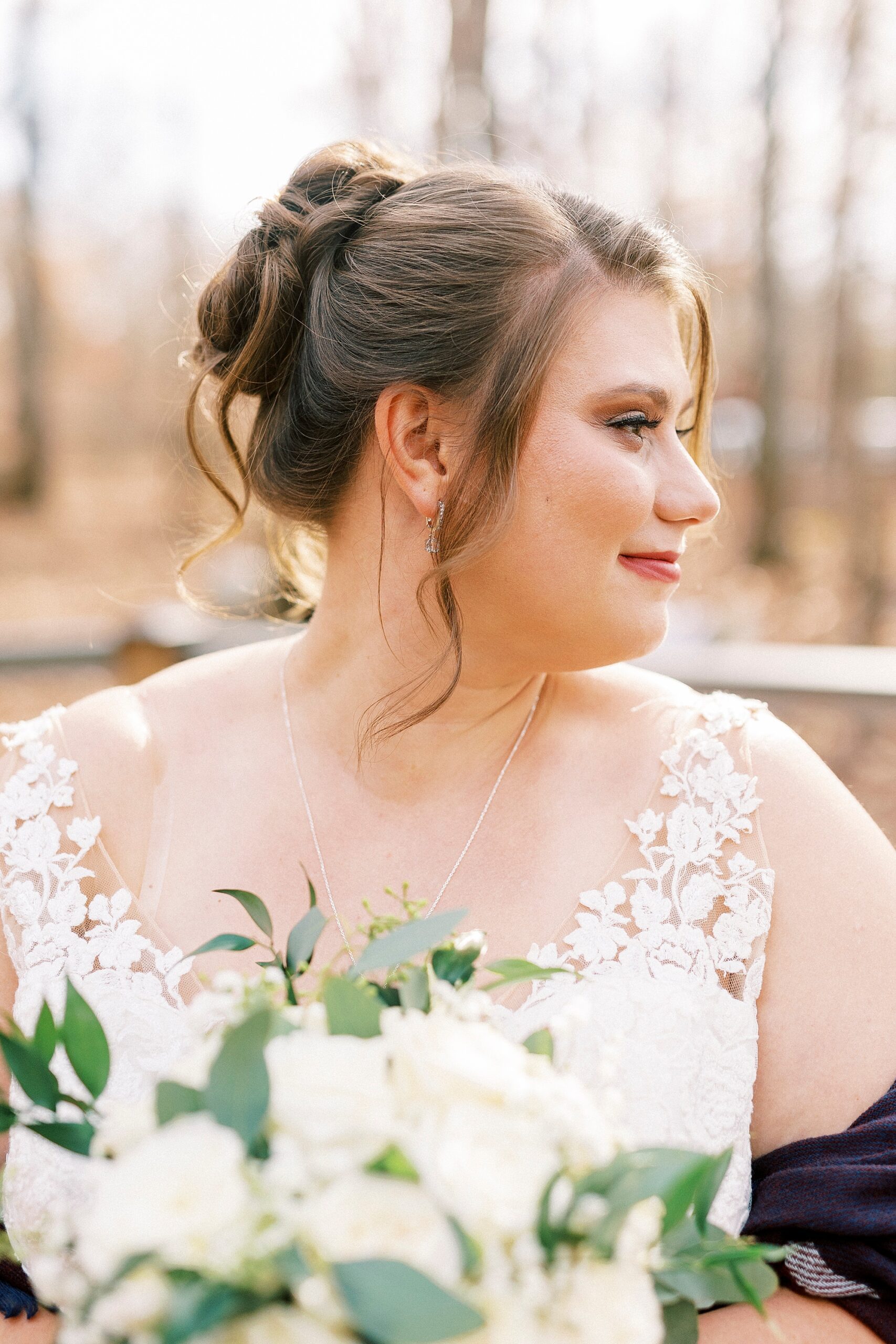 bride smiles over her shoulder with shawl around her and white floral bouquet 