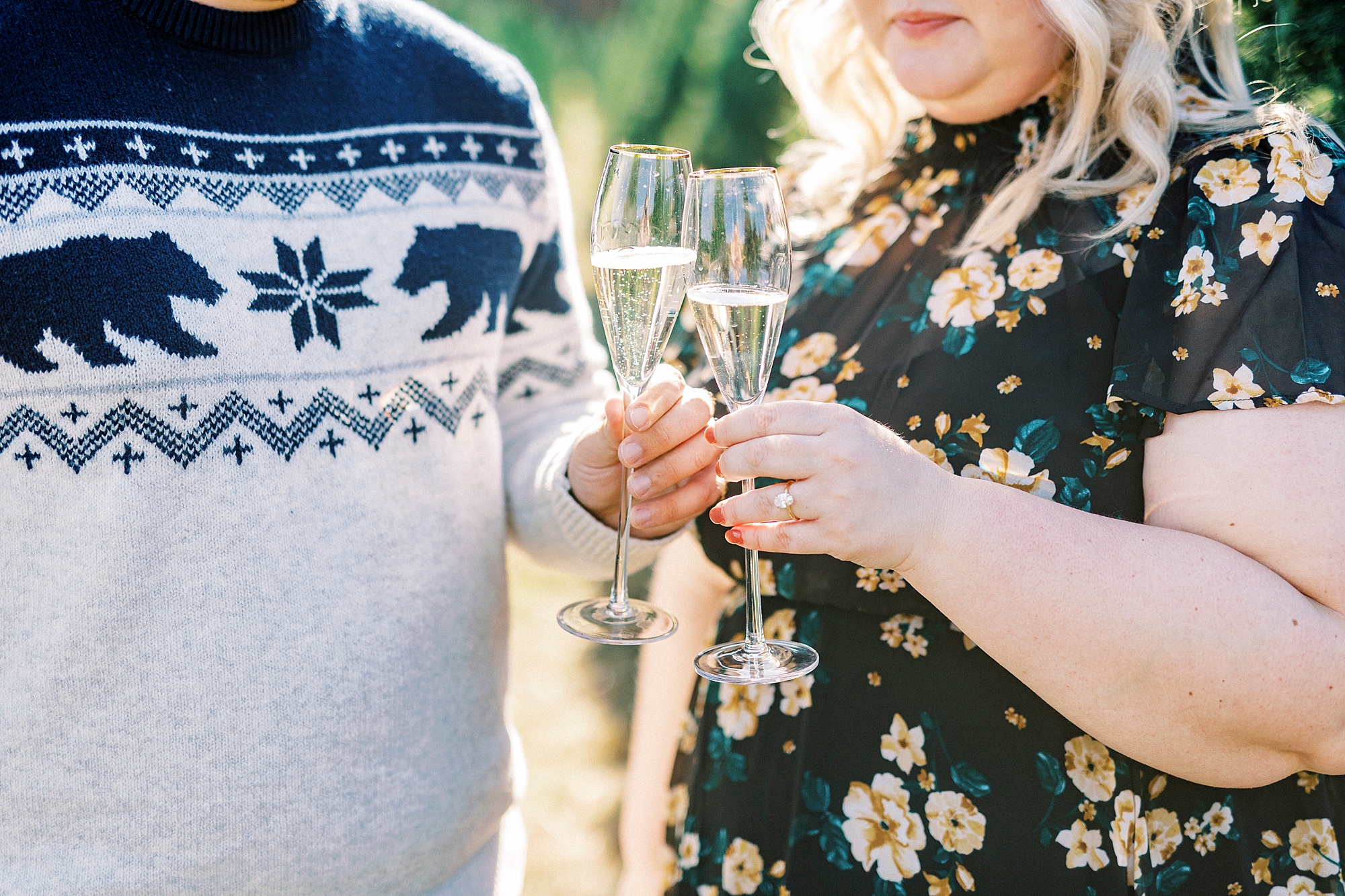 engaged couple toasts Champagne glasses during holiday mini sessions at tree farm