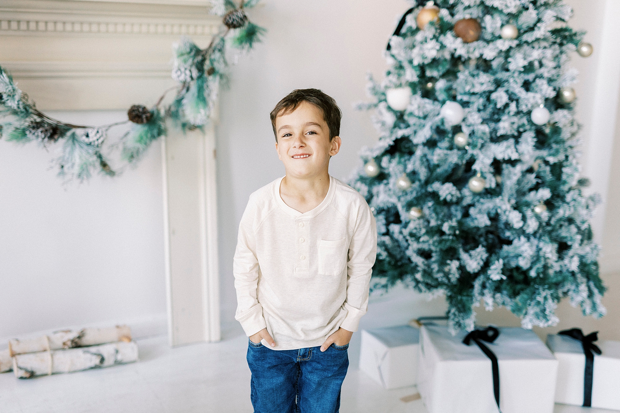 boy stands with hands in pockets of jeans during Christmas portraits in Downtown Concord studio