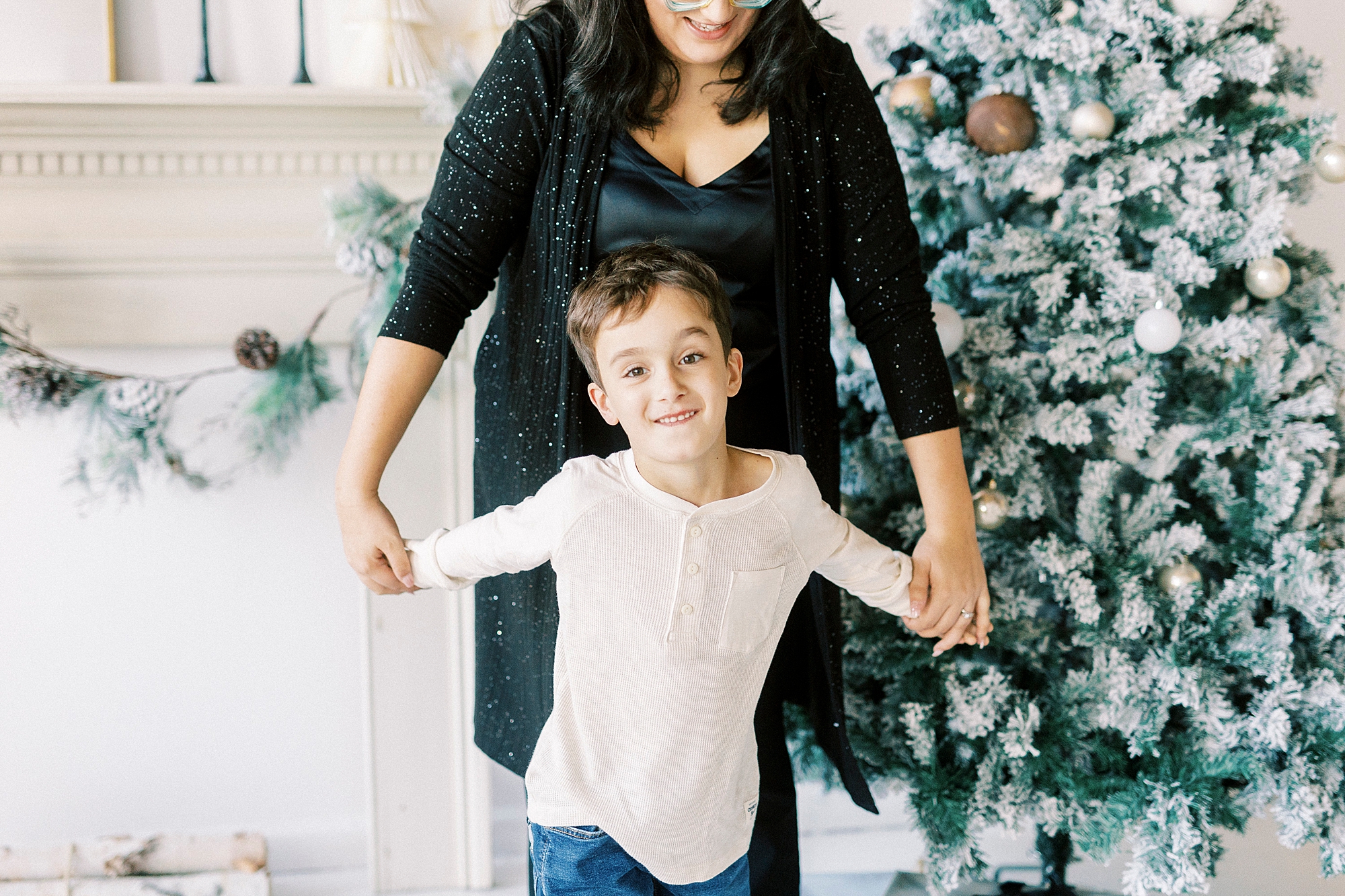 mom holds son's hands during Christmas portraits in Downtown Concord studio