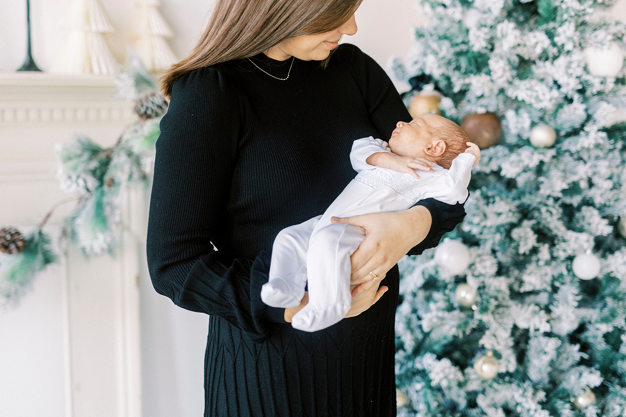 mom in black dress holds baby boy during studio Christmas portraits in Downtown Concord