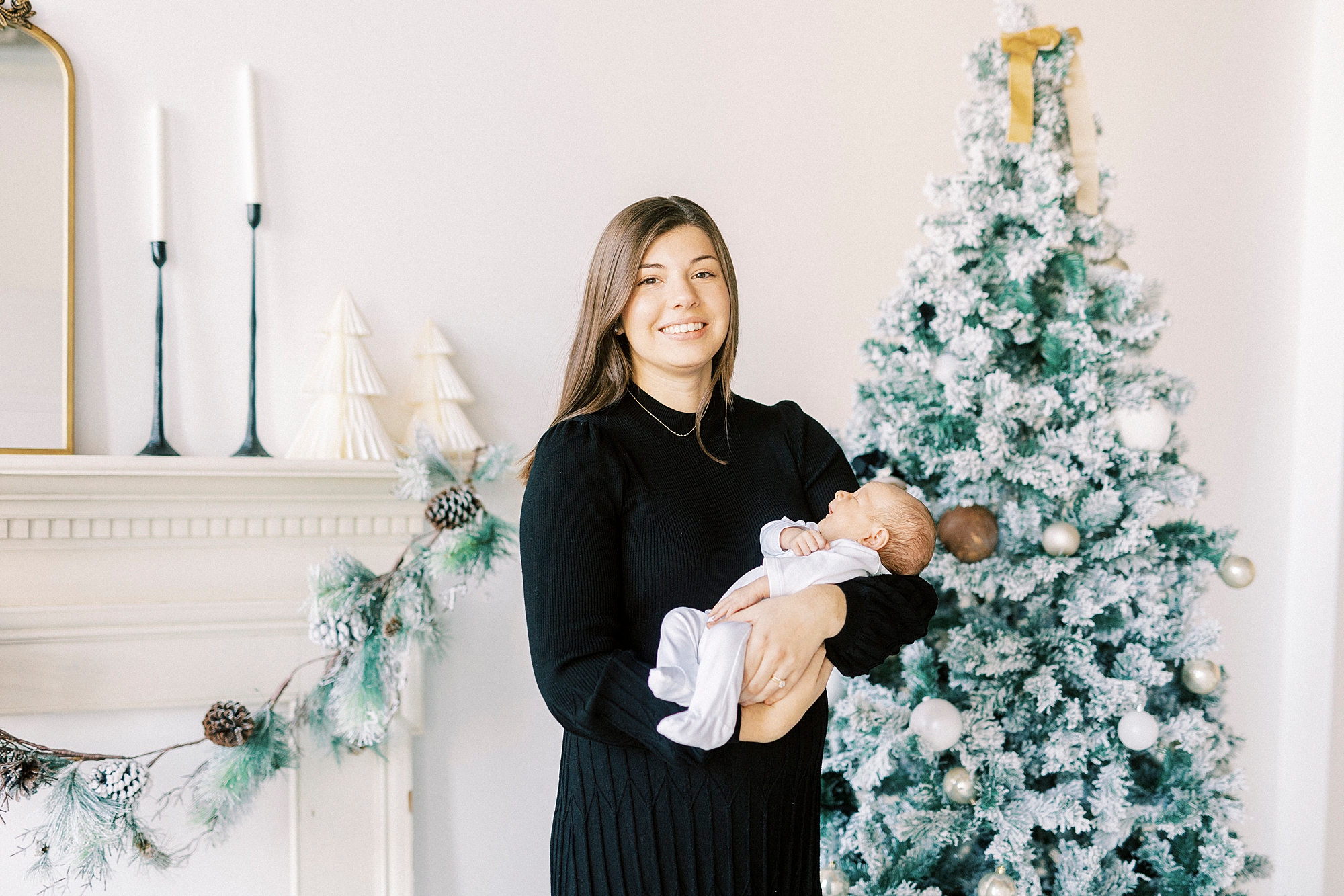 woman holds baby in front of Christmas tree during studio portraits 