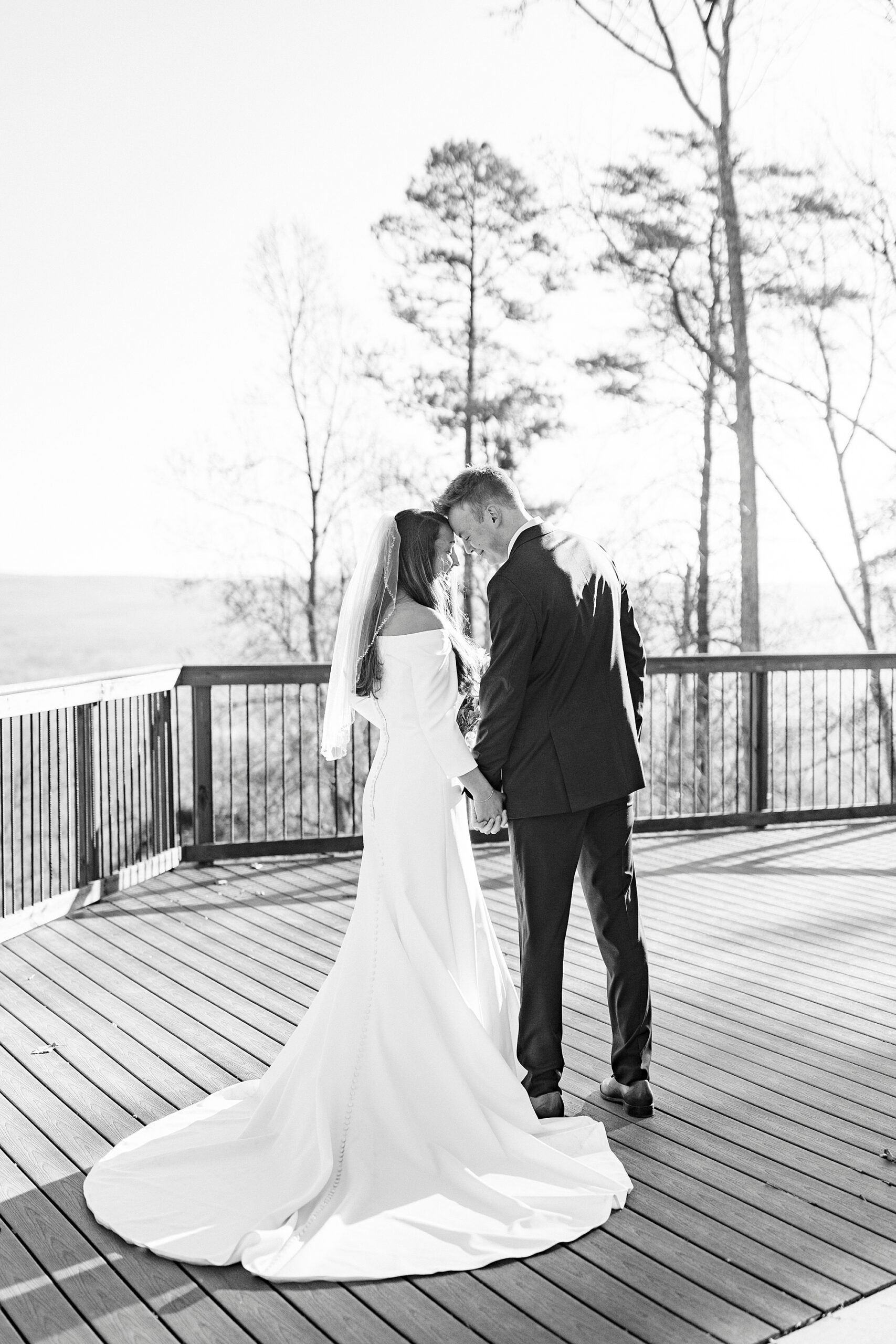 bride and groom lean heads together on wooden patio at Morrow Mountain