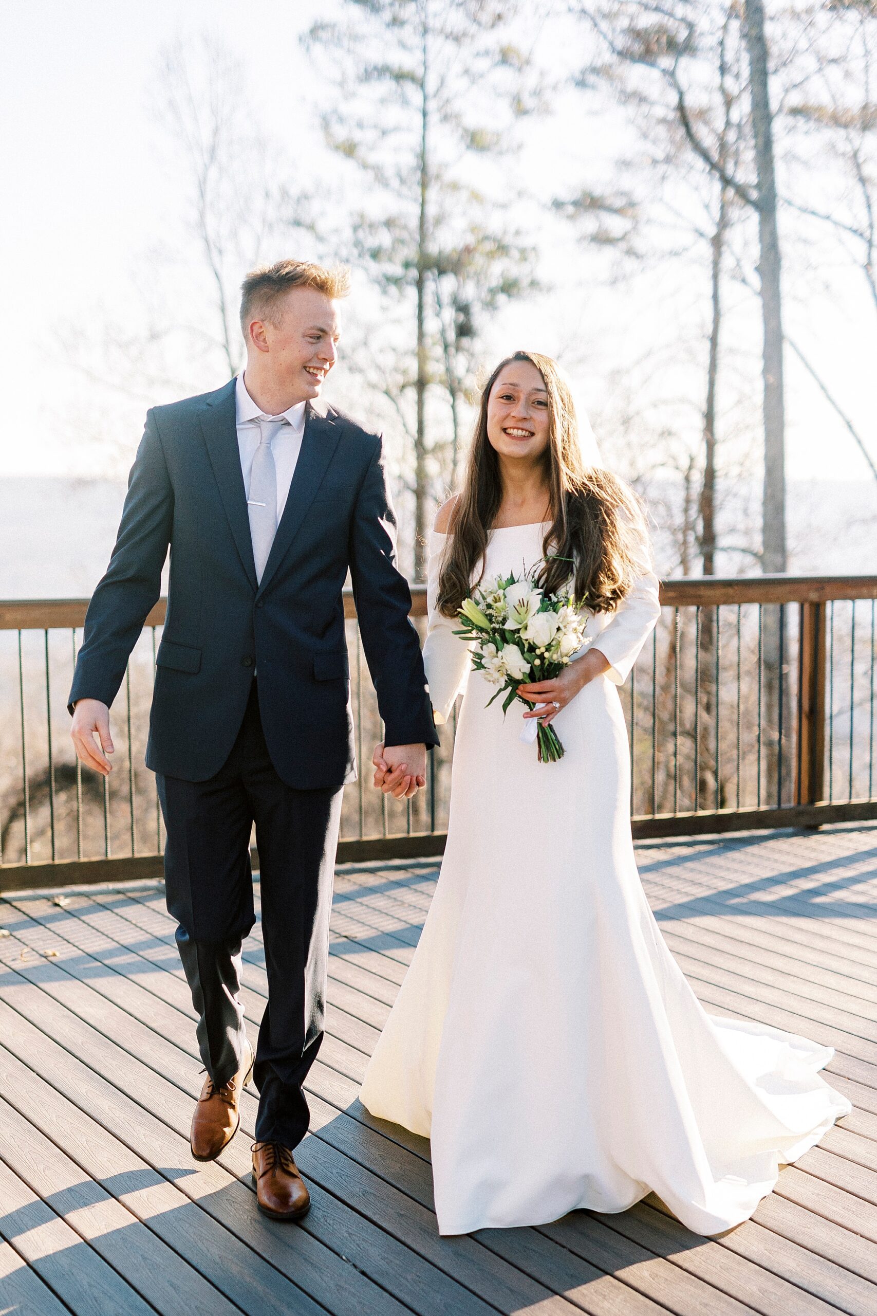 bride and groom hold hands walking on patio of Morrow Mountain