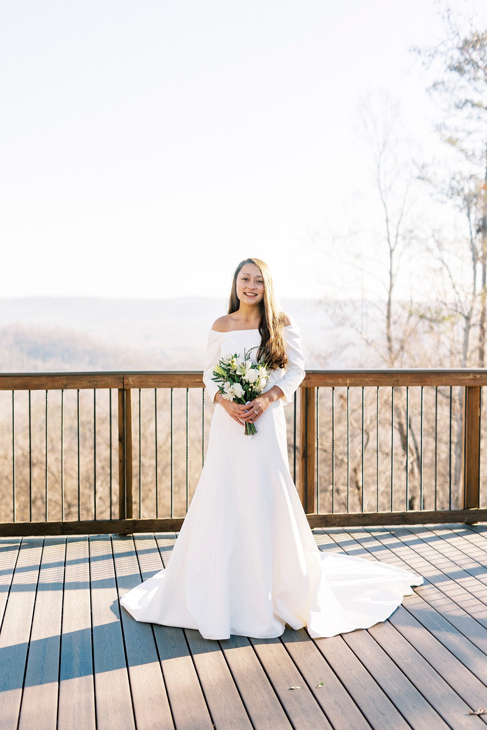 bride stands holding bouquet of ivory flowers