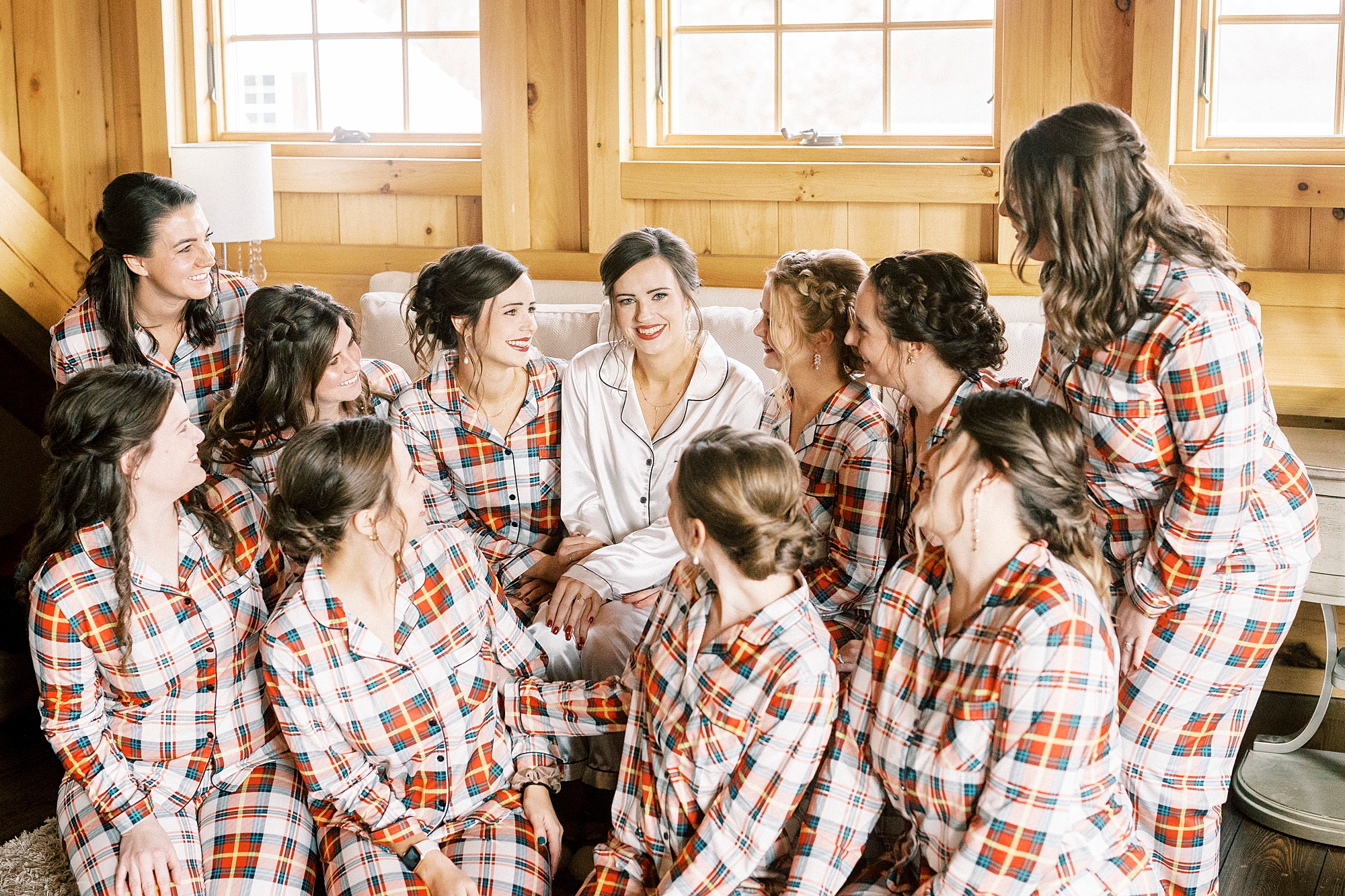 bride sits with bridesmaids in plaid pajamas during prep for NC wedding day