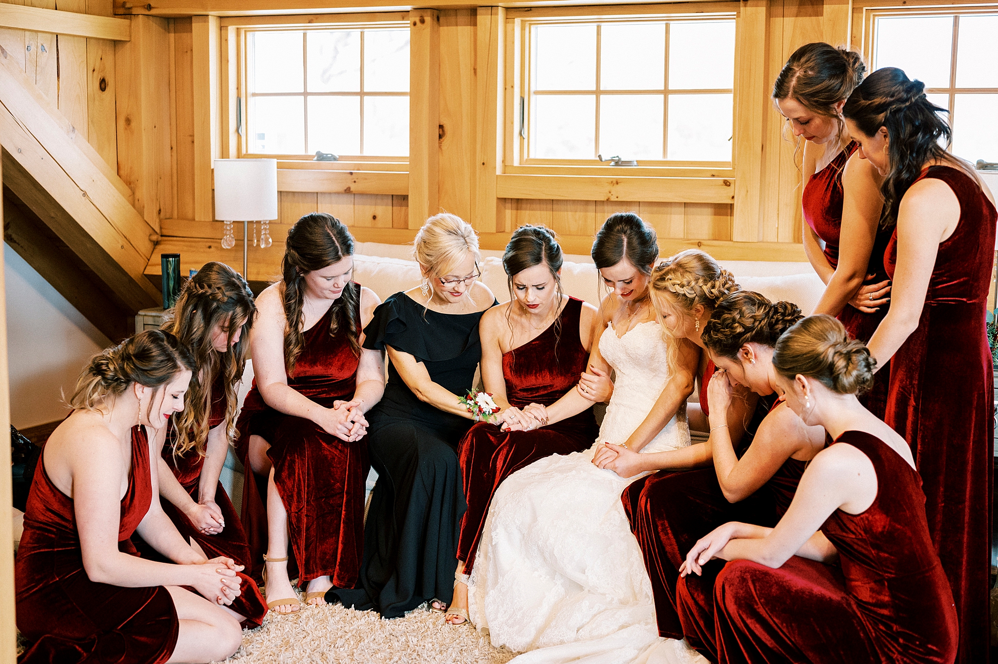 bride prays with bridesmaids and mother inside suite at Chickadee Hill Farms