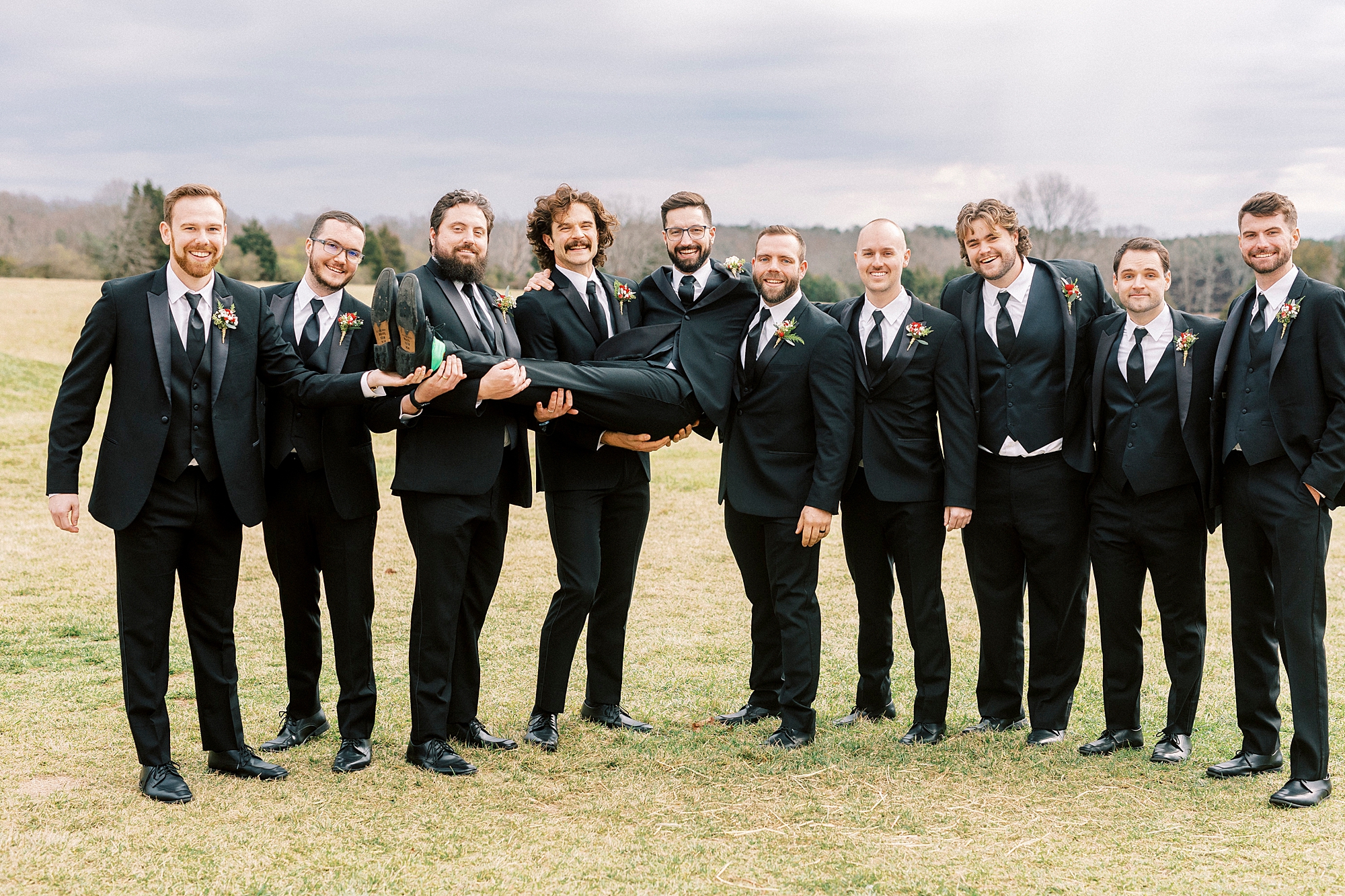 groomsmen hold up groom during portraits for winter Chickadee Hill Farms wedding