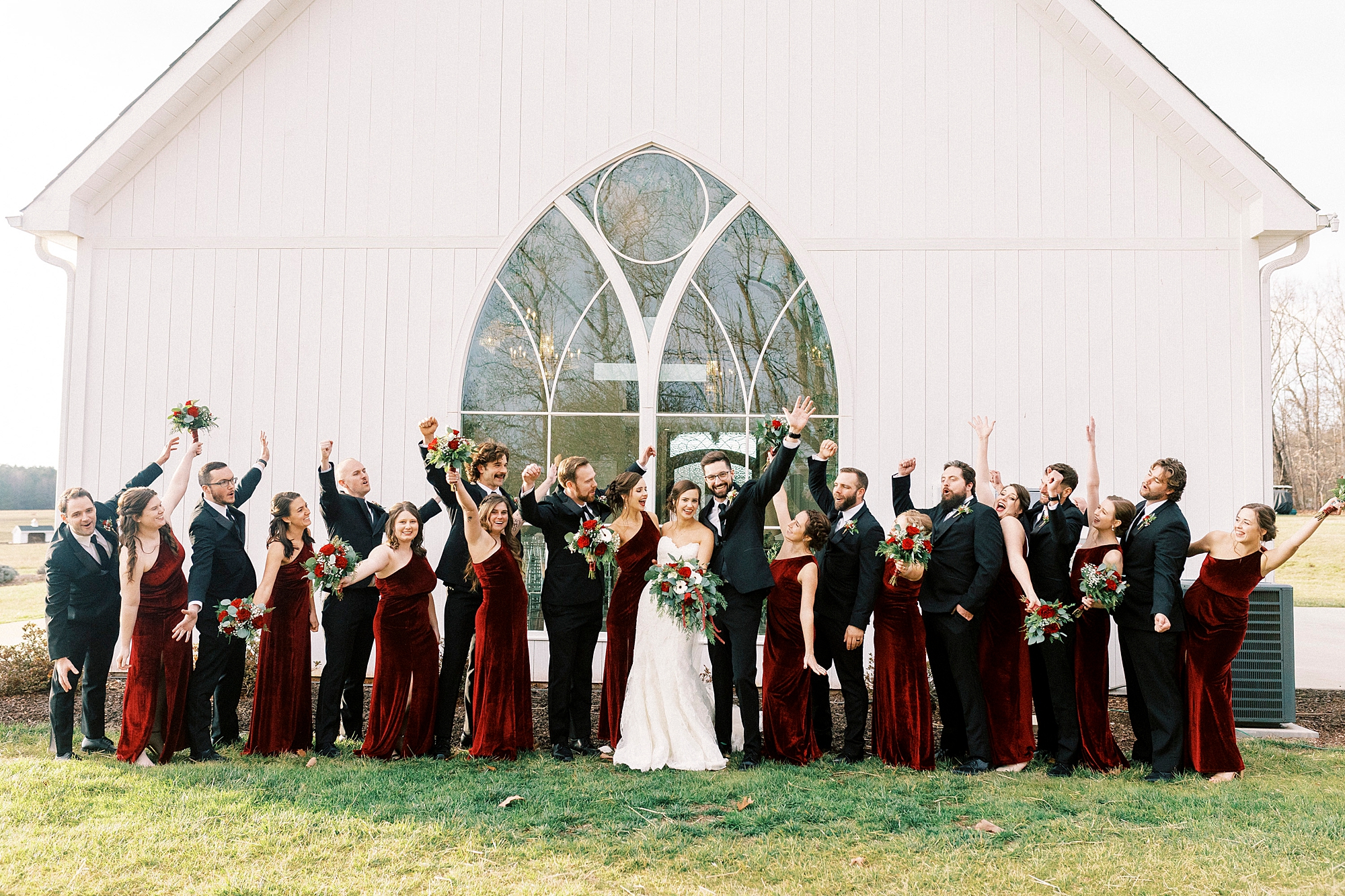 bride and groom stand with wedding party cheering in front of chapel at Chickadee Hill Farms