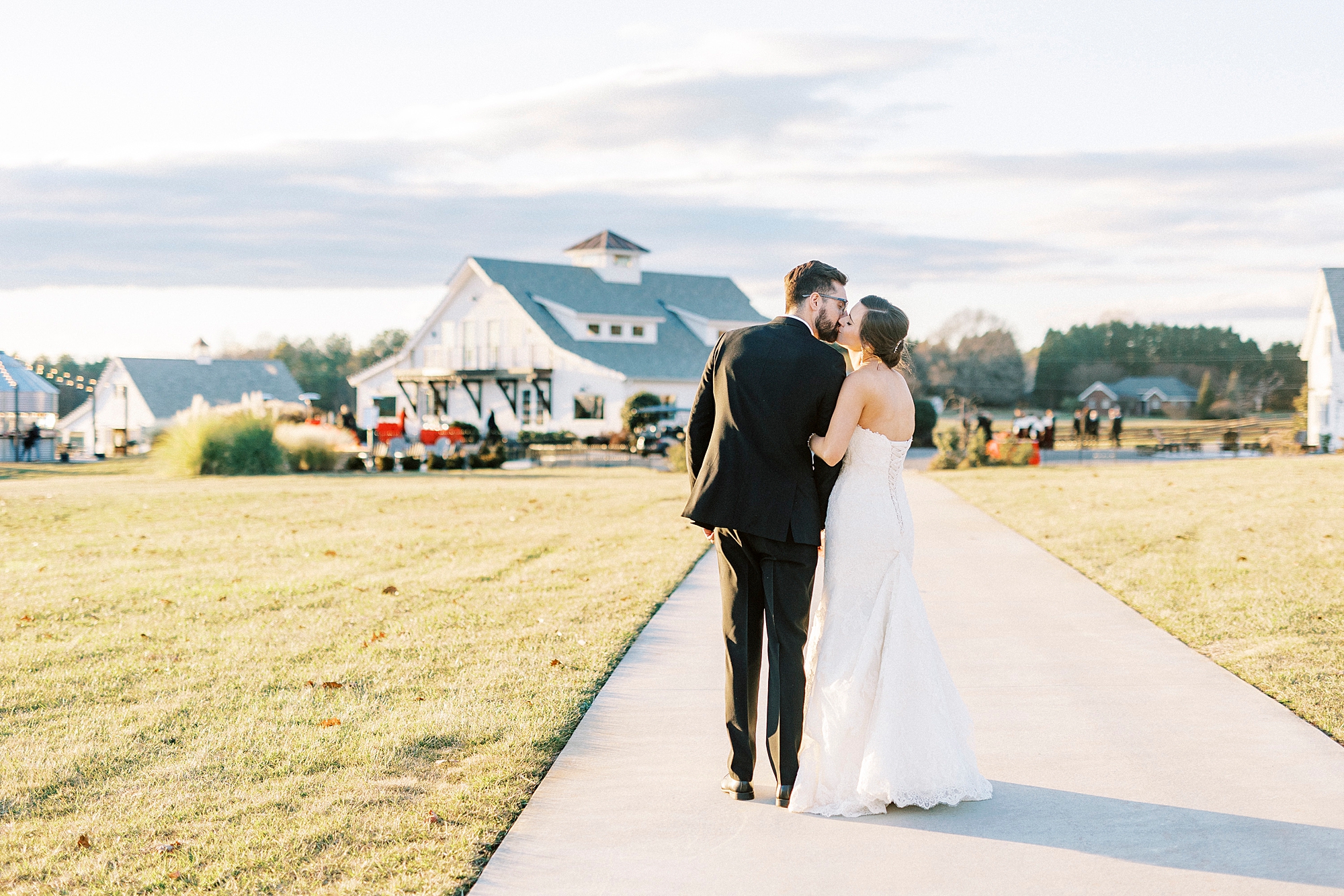 bride and groom kiss on sidewalk in front of Chickadee Hill Farms