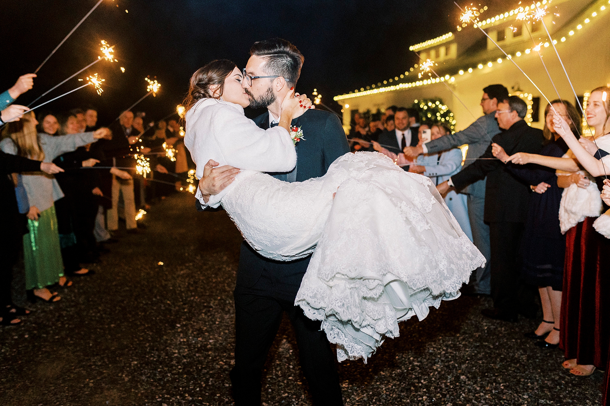 groom lifts up bride kissing her during sparkler exit from Statesville NC wedding reception 