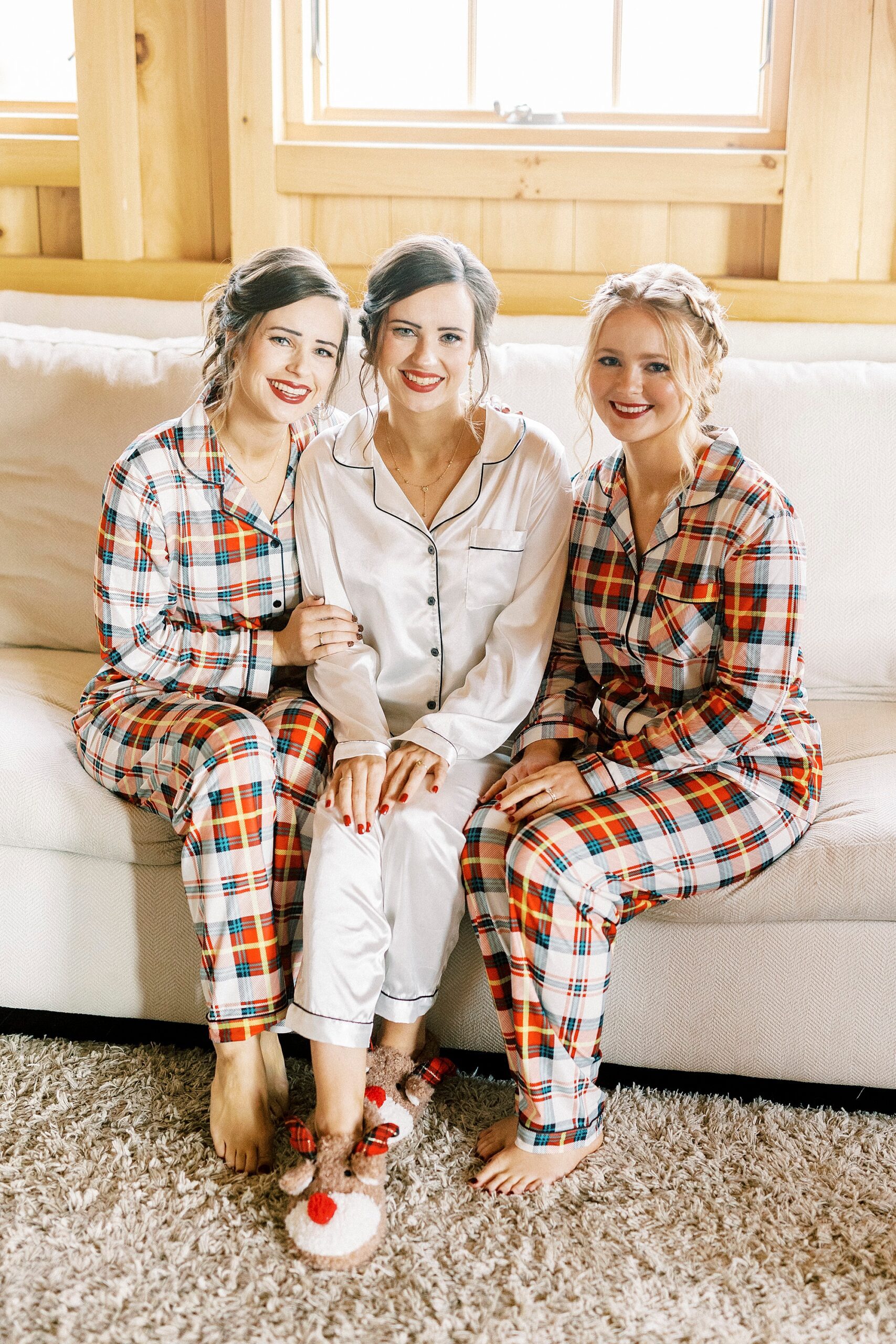 bride sits on couch with bridesmaids in matching red plaid pajamas 