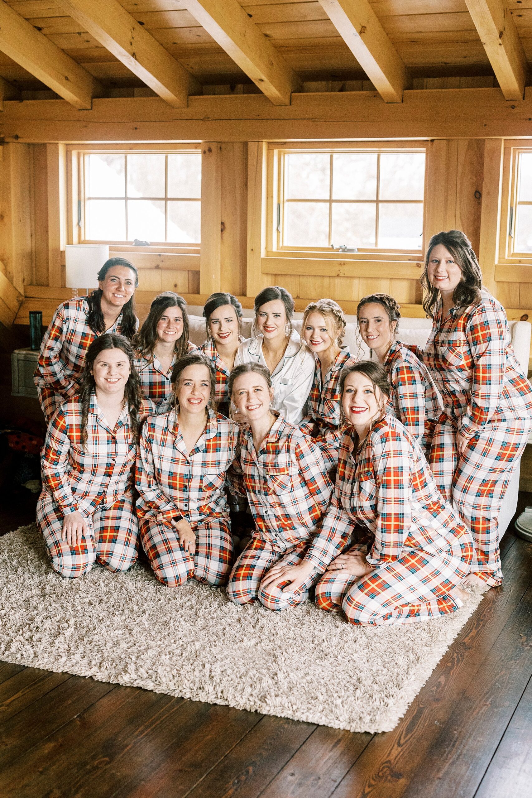 bride poses with bridesmaids in plaid Christmas pajamas at Chickadee Hill Farms