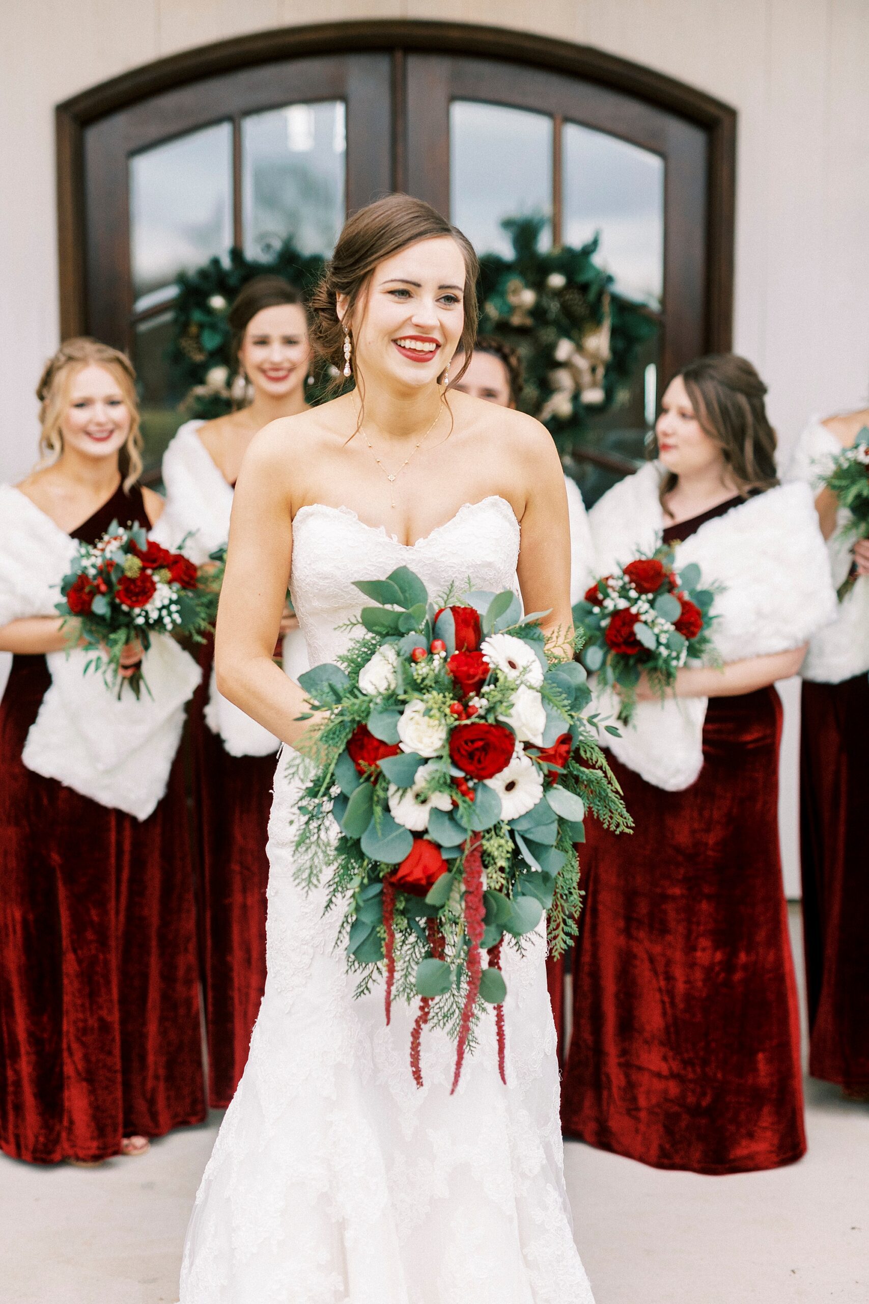 bride smiles holding bouquet of red and white flowers for winter Chickadee Hill Farms wedding