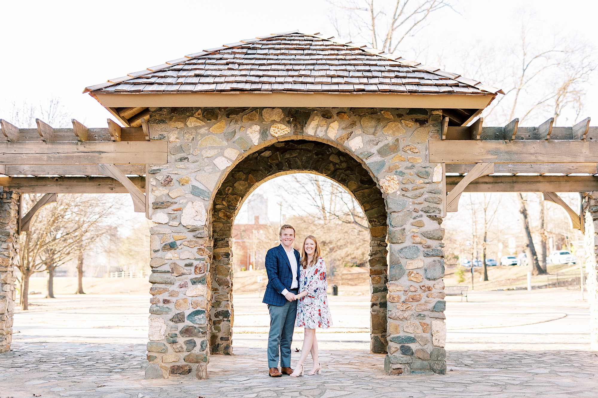 bride and groom hold hands standing together under stone arch at Independence Park