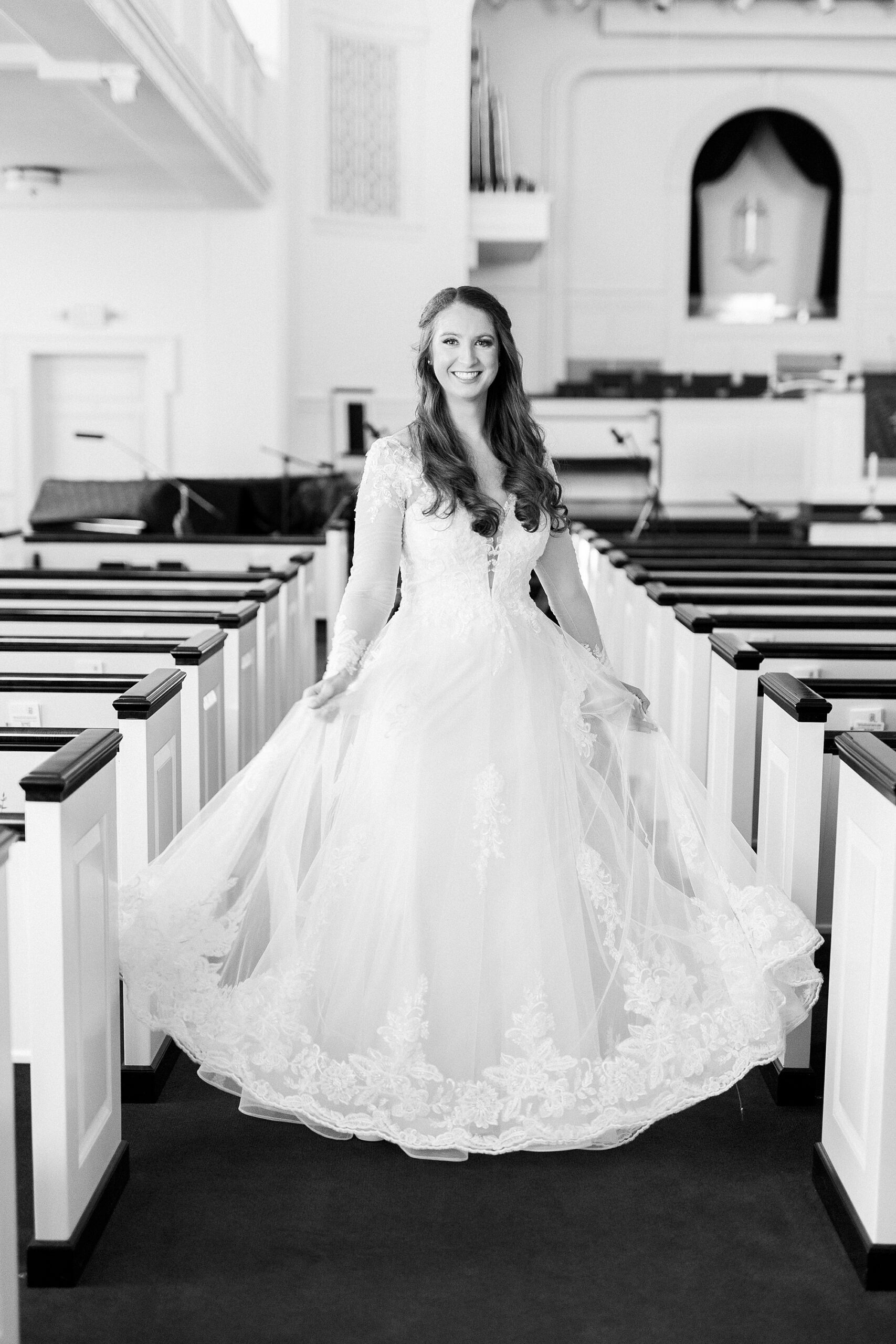 bride twirls with wedding dress skirt out in aisle at Downtown Kannapolis church