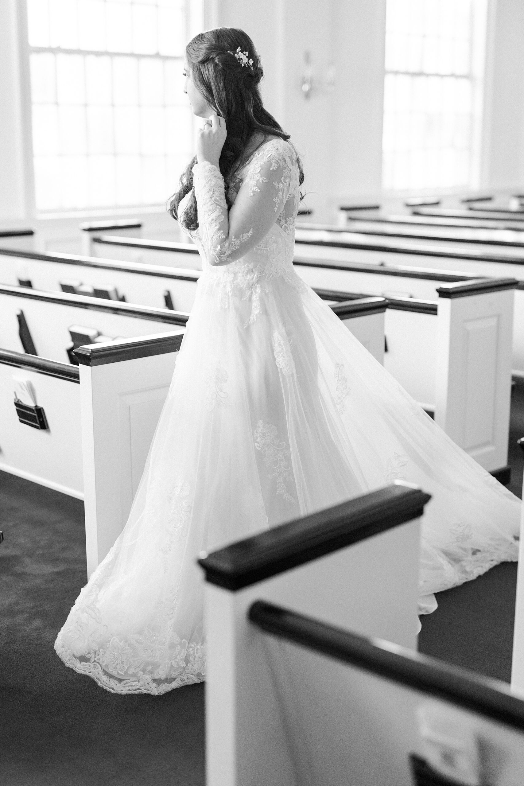 bride in wedding gown with lace sleeves walks down aisle inside church 