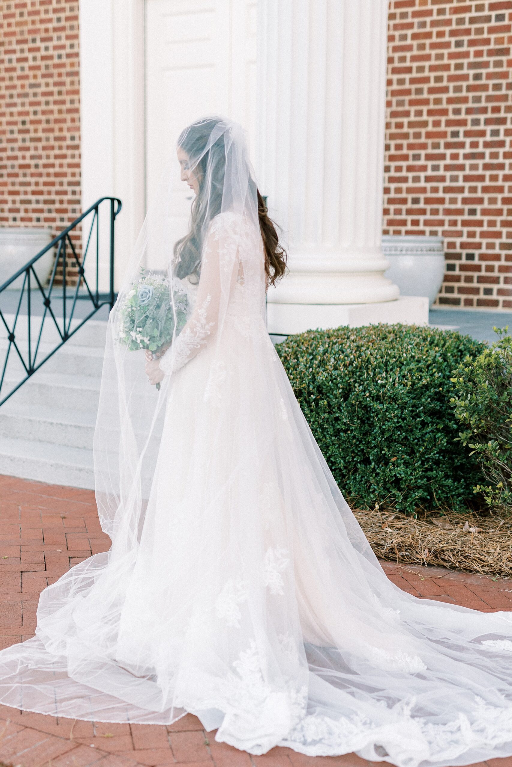 bride looks down under veil during bridal portraits in Downtown Kannapolis