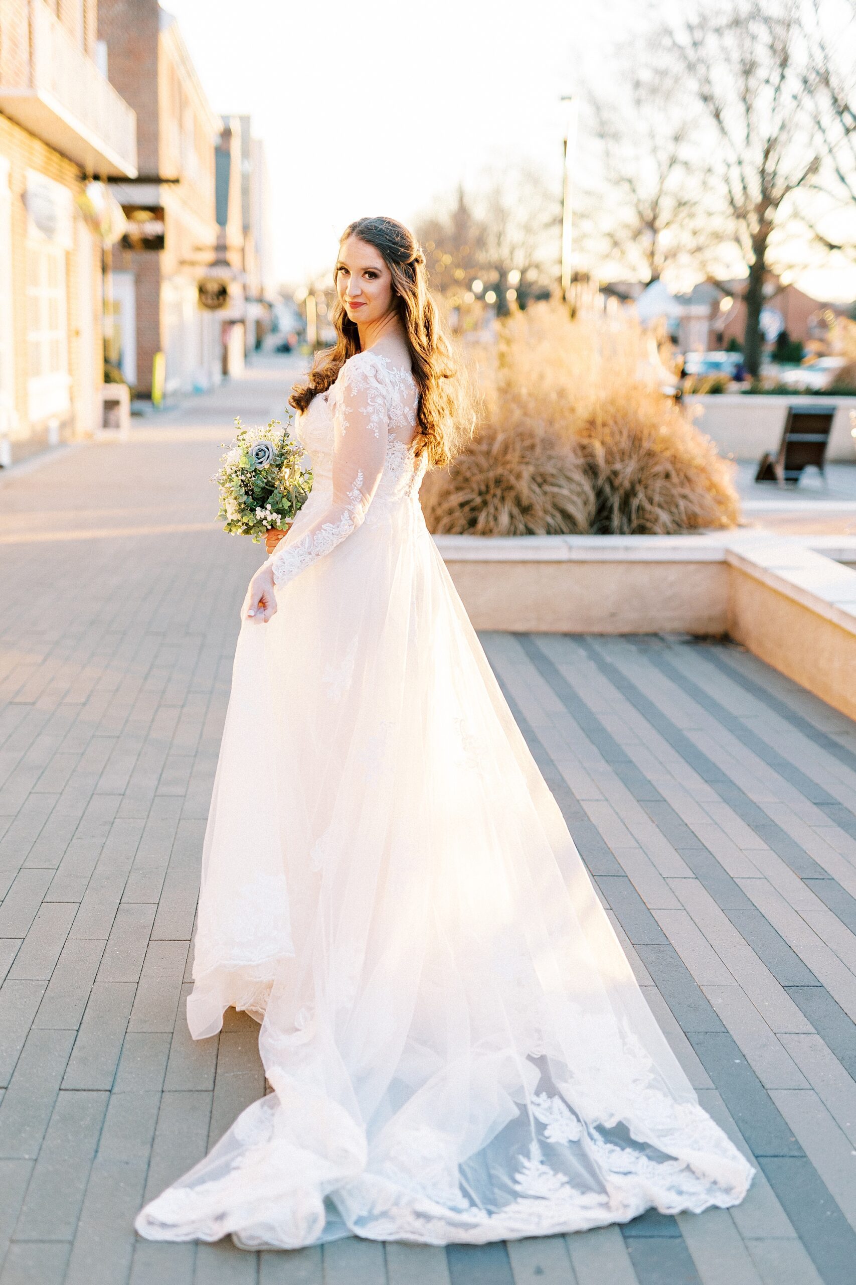 bride walks in Downtown Kannapolis carrying skirt of wedding dress