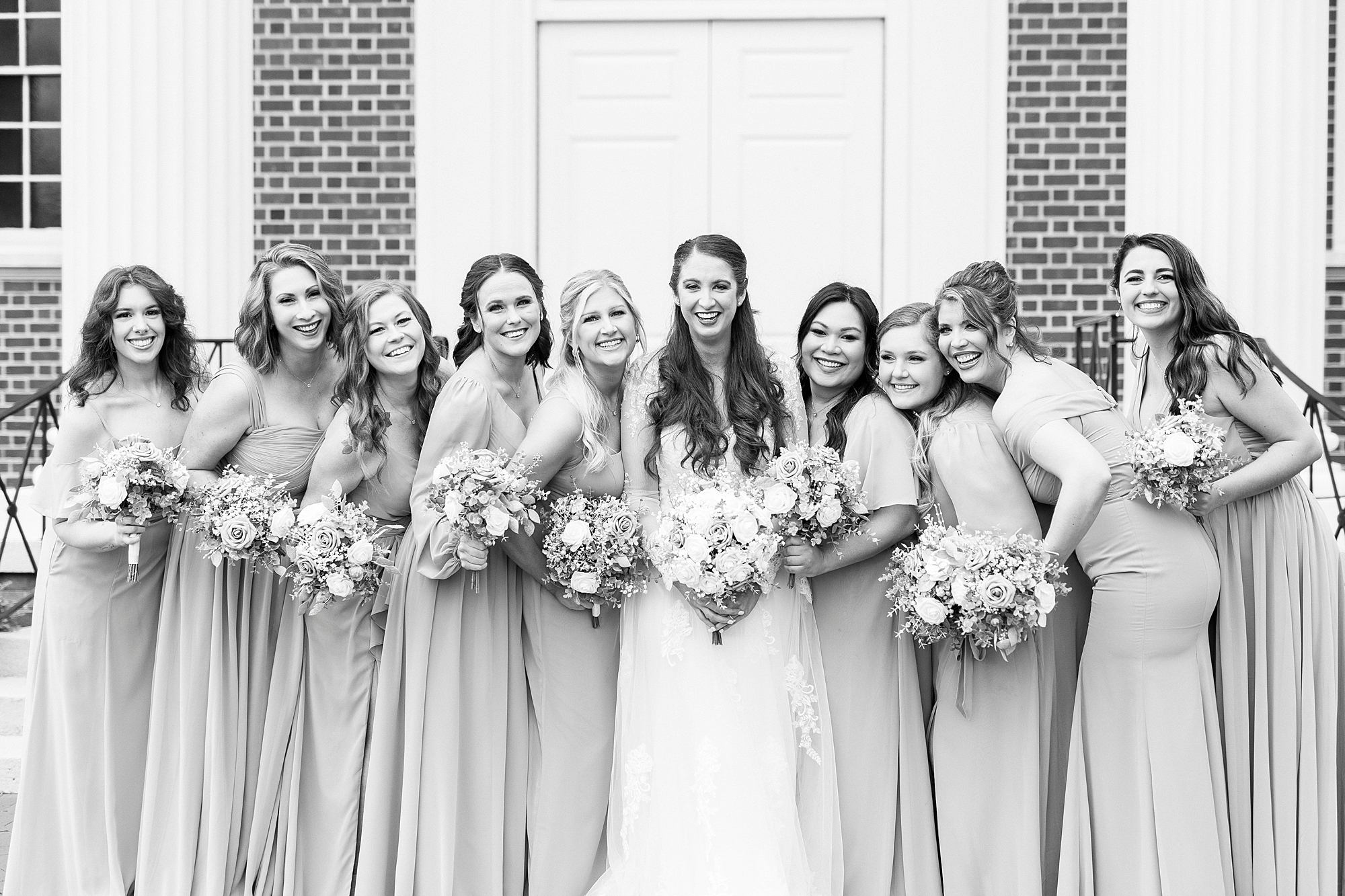 bride and bridesmaids hug together outside First Baptist Church in Kannapolis NC