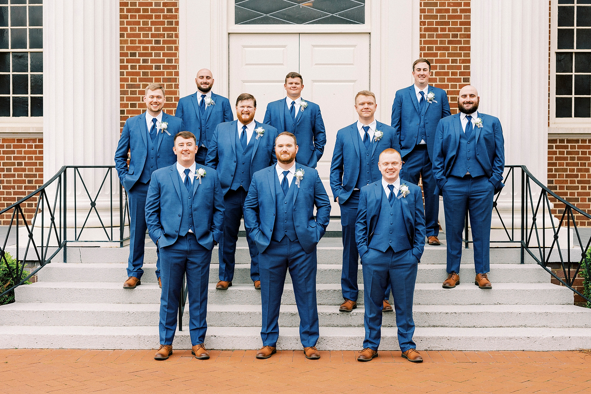 groom stands with groomsmen in navy suits on steps of First Baptist Church in Kannapolis NC