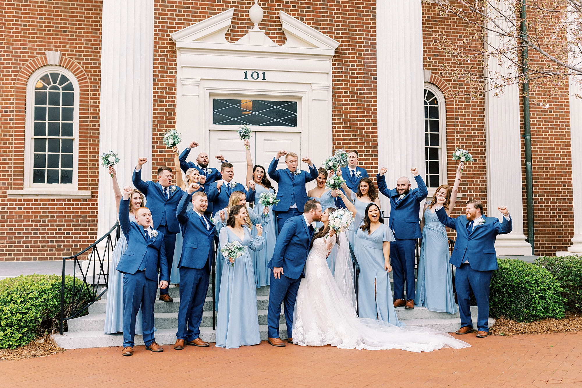 bride and groom kiss on steps outside First Baptist Church in Kannapolis NC in blue attire