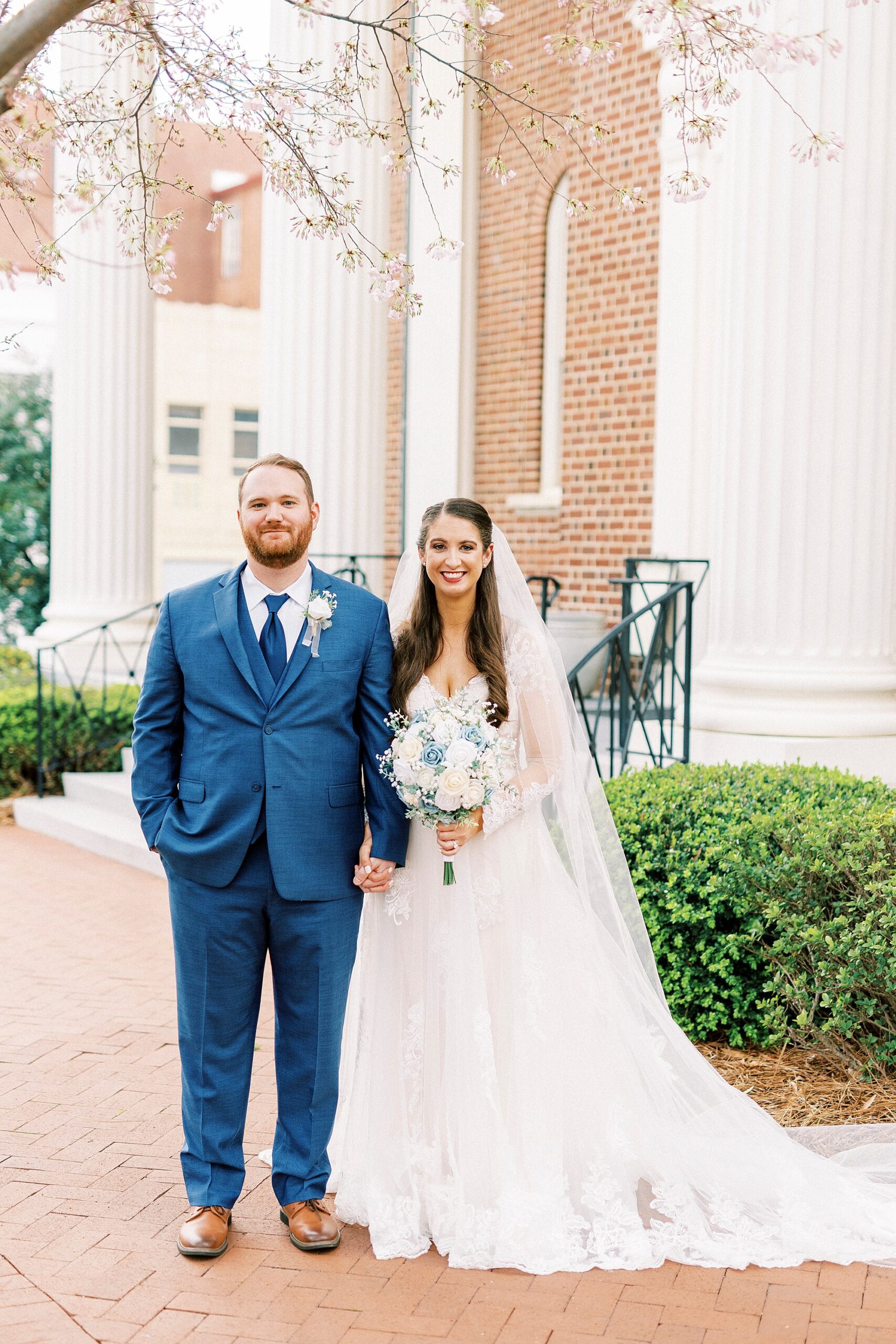 bride and groom hold hands standing outside church in Downtown Kannapolis