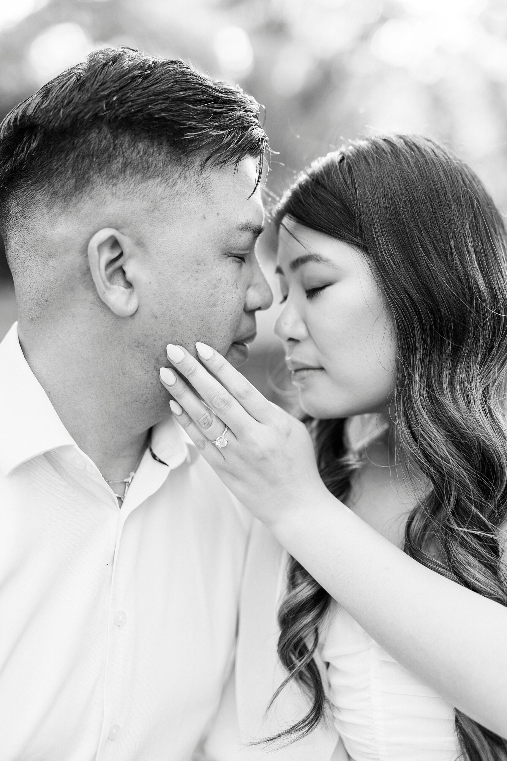 woman holds man's jaw showing off her engagement ring 