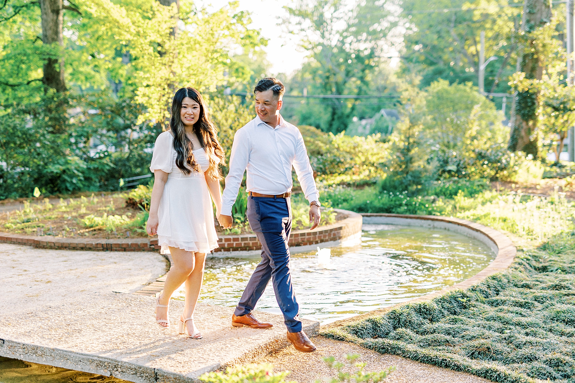 man leads woman over wooden bridge on the pond at Glencairn Garden