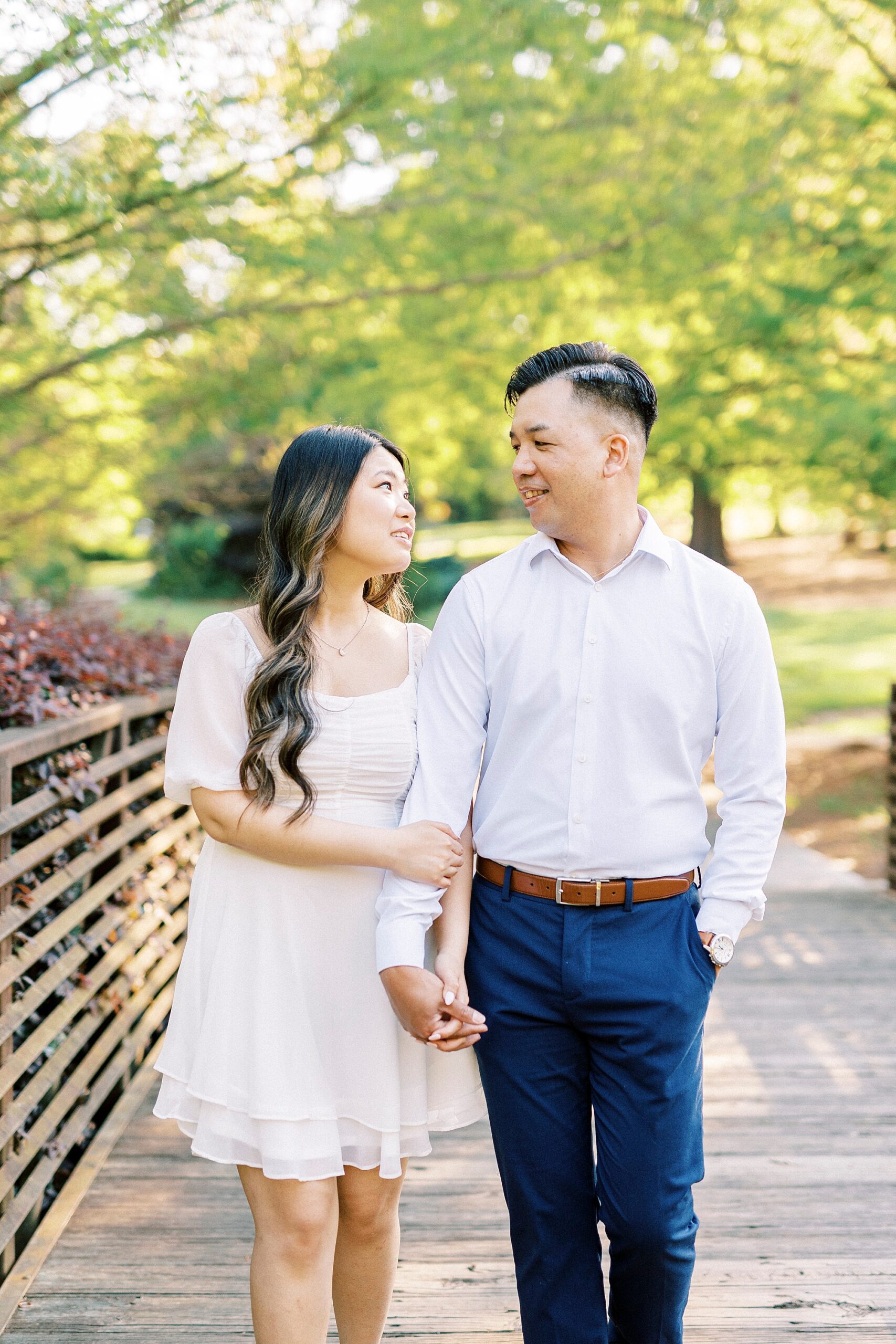 woman smiles looking at man with her hand on his arm on bridge 