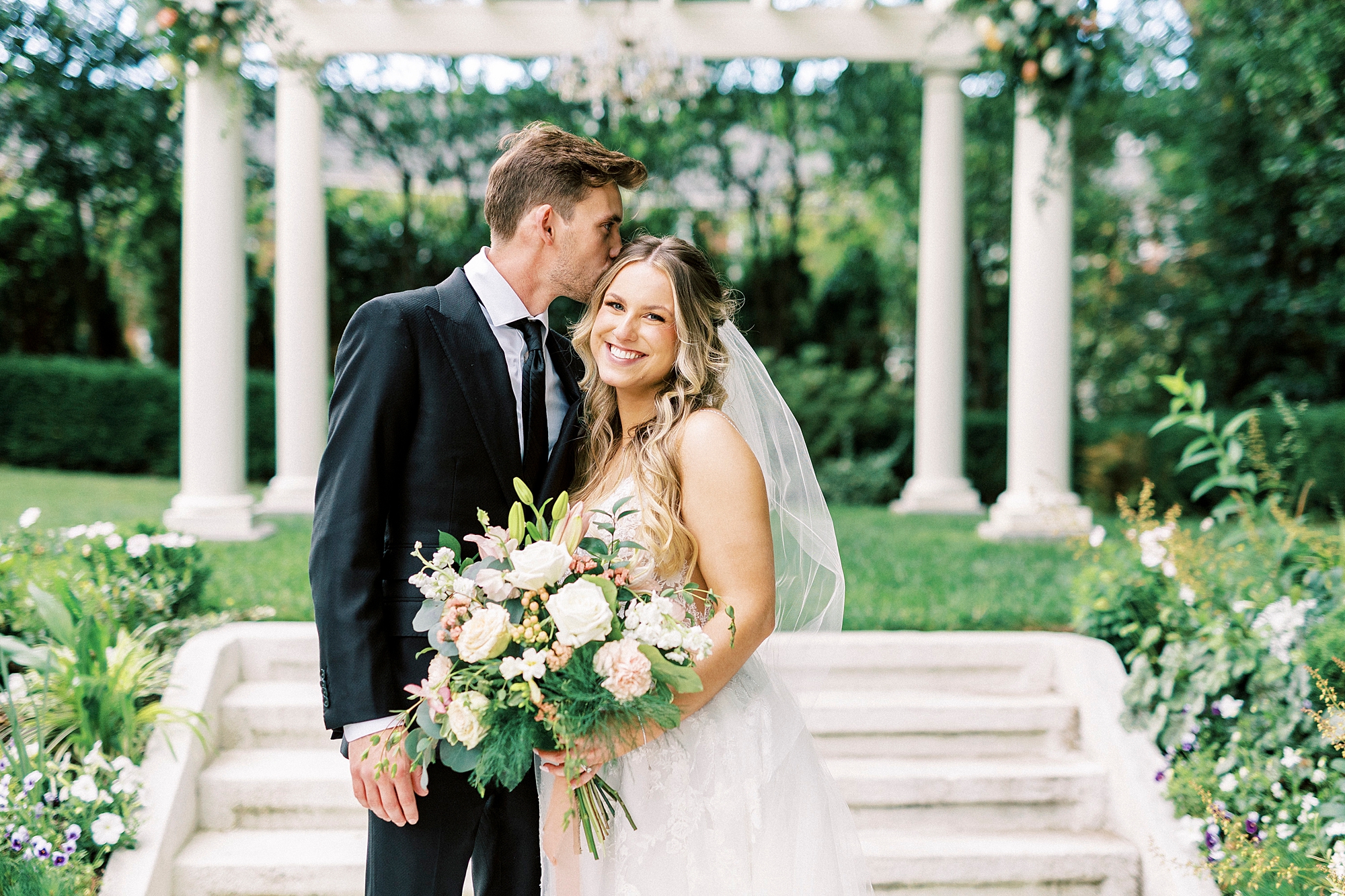 groom kisses bride's forehead during garden wedding at Separk Mansion