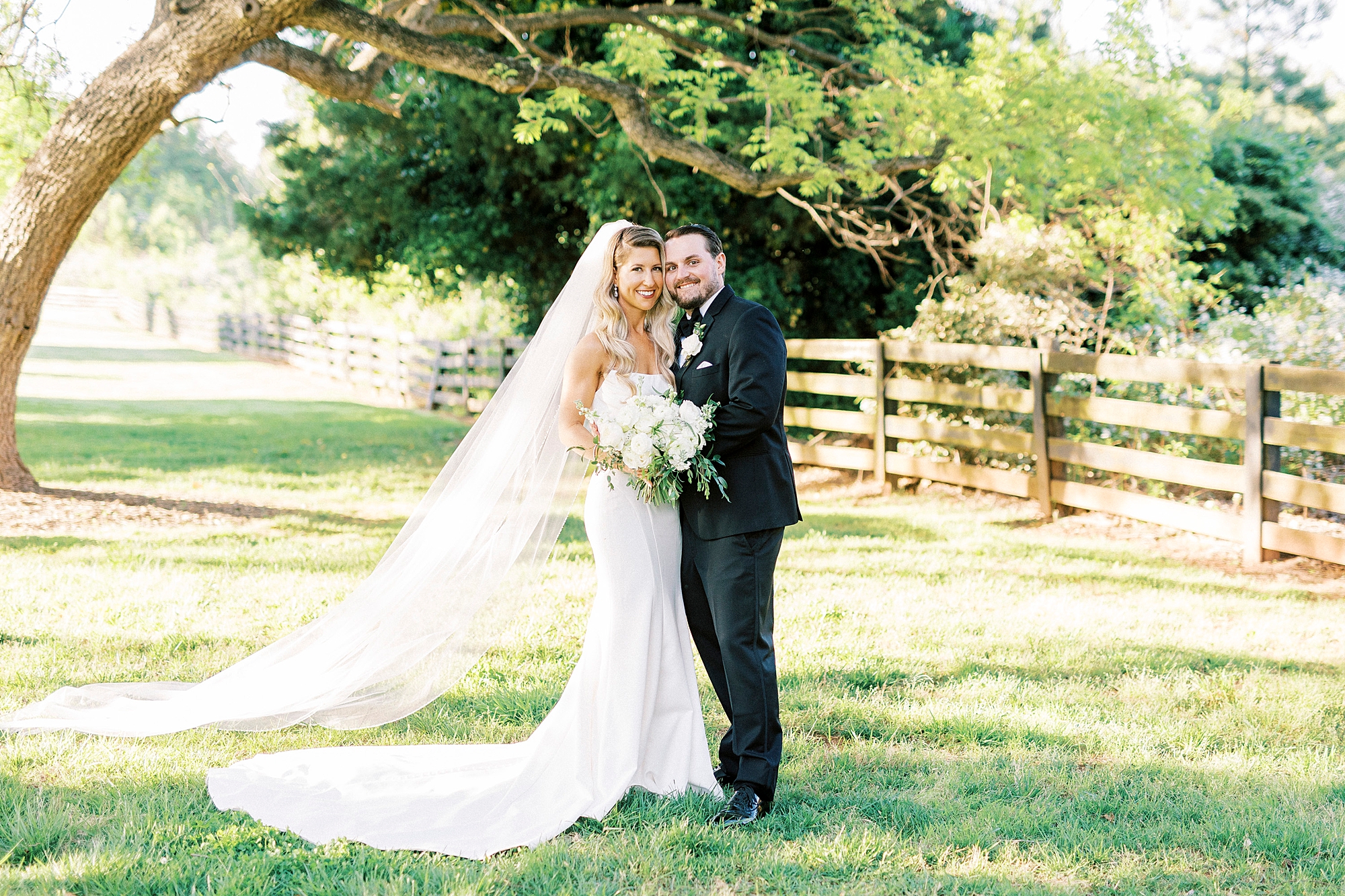 newlyweds hug under tree in field at the Venues at Langtree