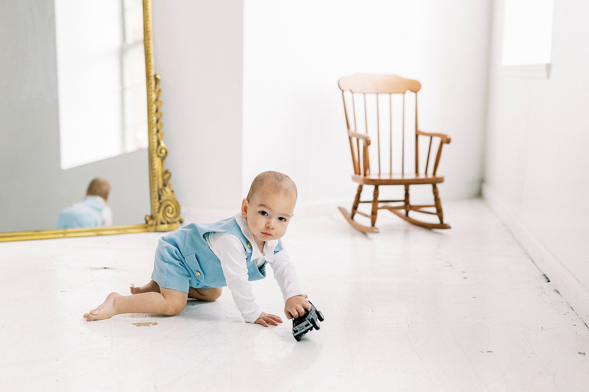 baby crawls on studio floor in front of wooden chair