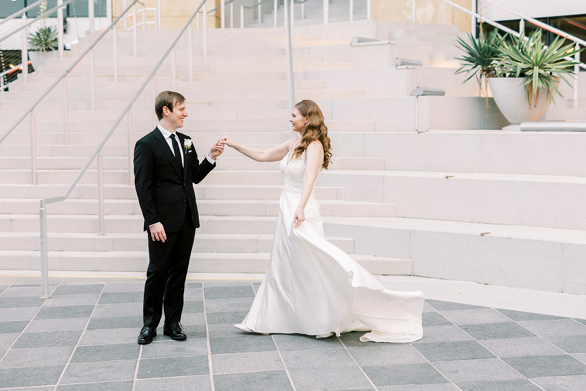 bride and groom hold hands in front of steps outside the Mint Museum Uptown