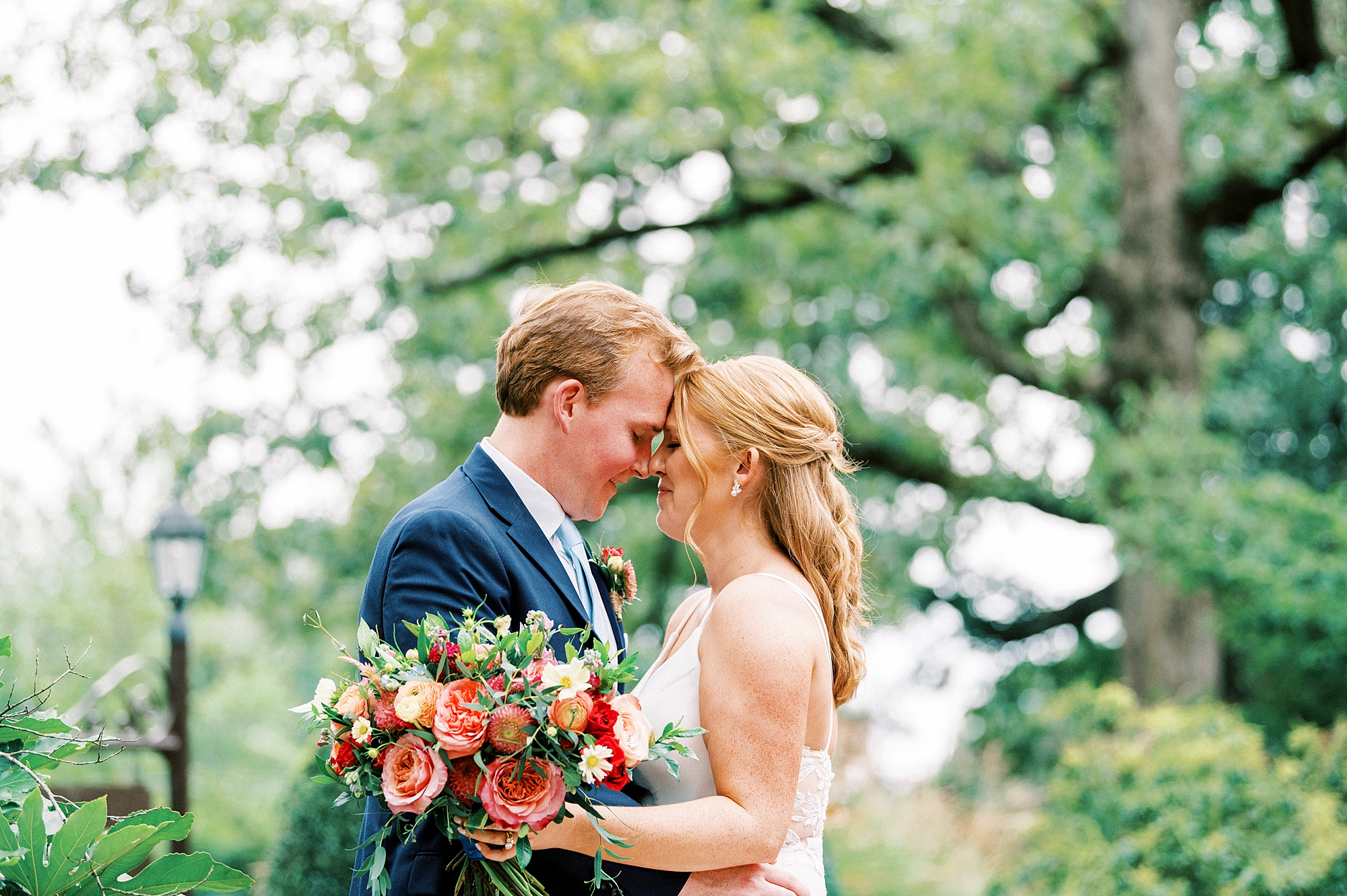 bride and groom lean heads together in garden at Whitehead Manor