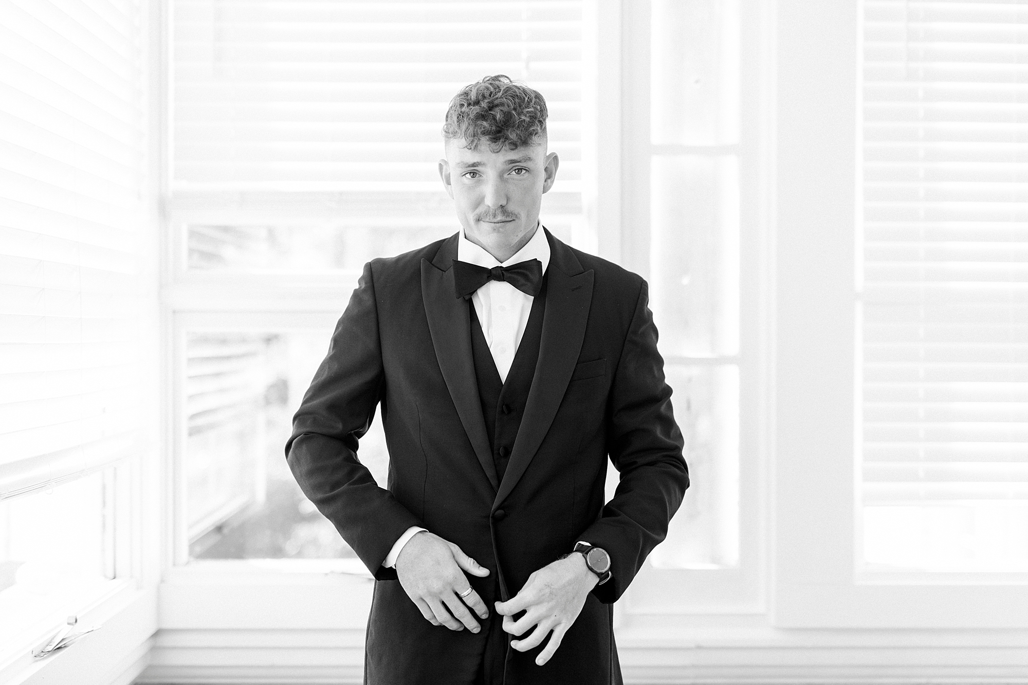 groom adjusts buttons on suit jacket during prep at Separk Mansion