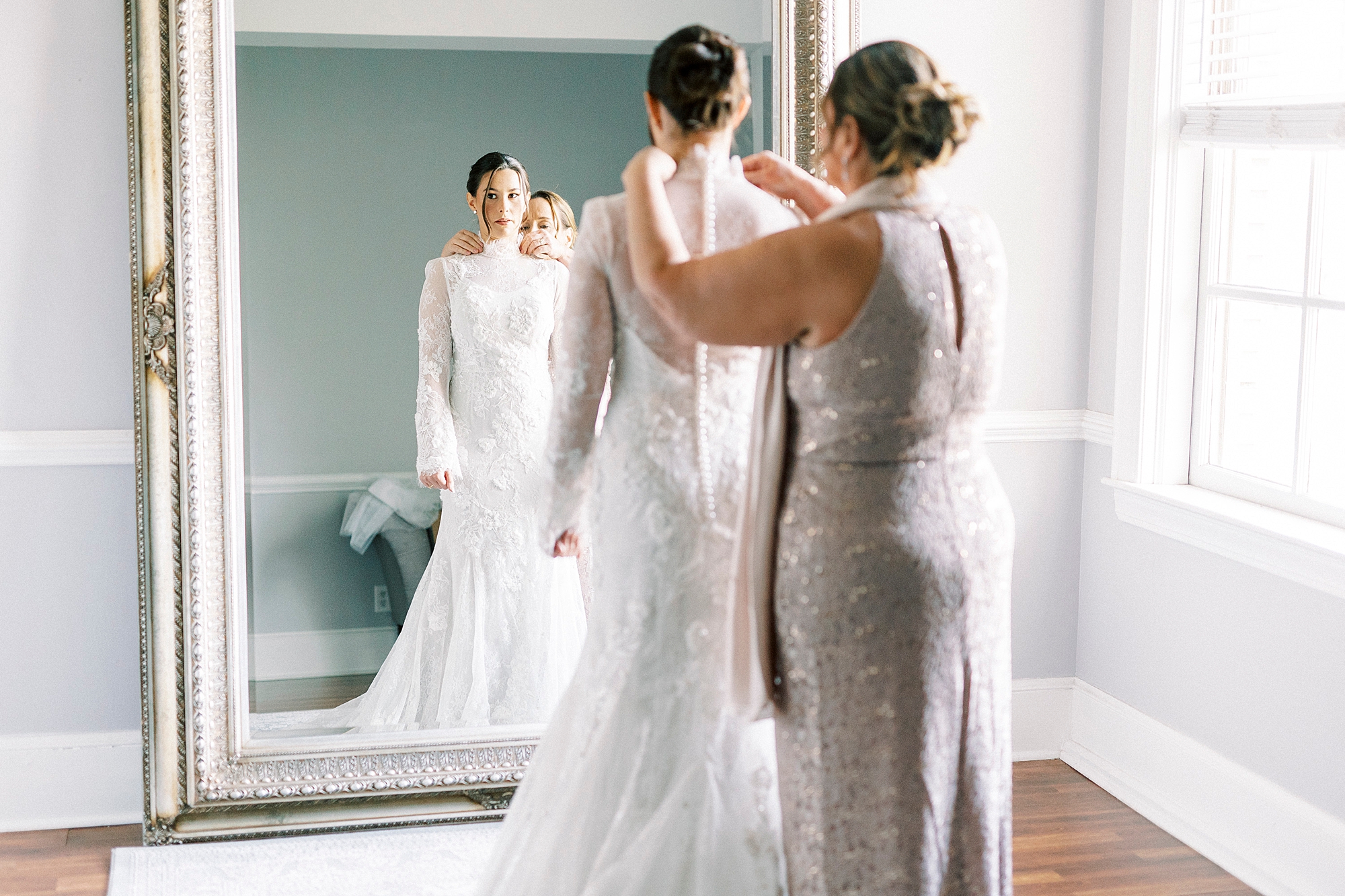 woman buttons up back of wedding gown lace buttons in front of mirror at Separk Mansion