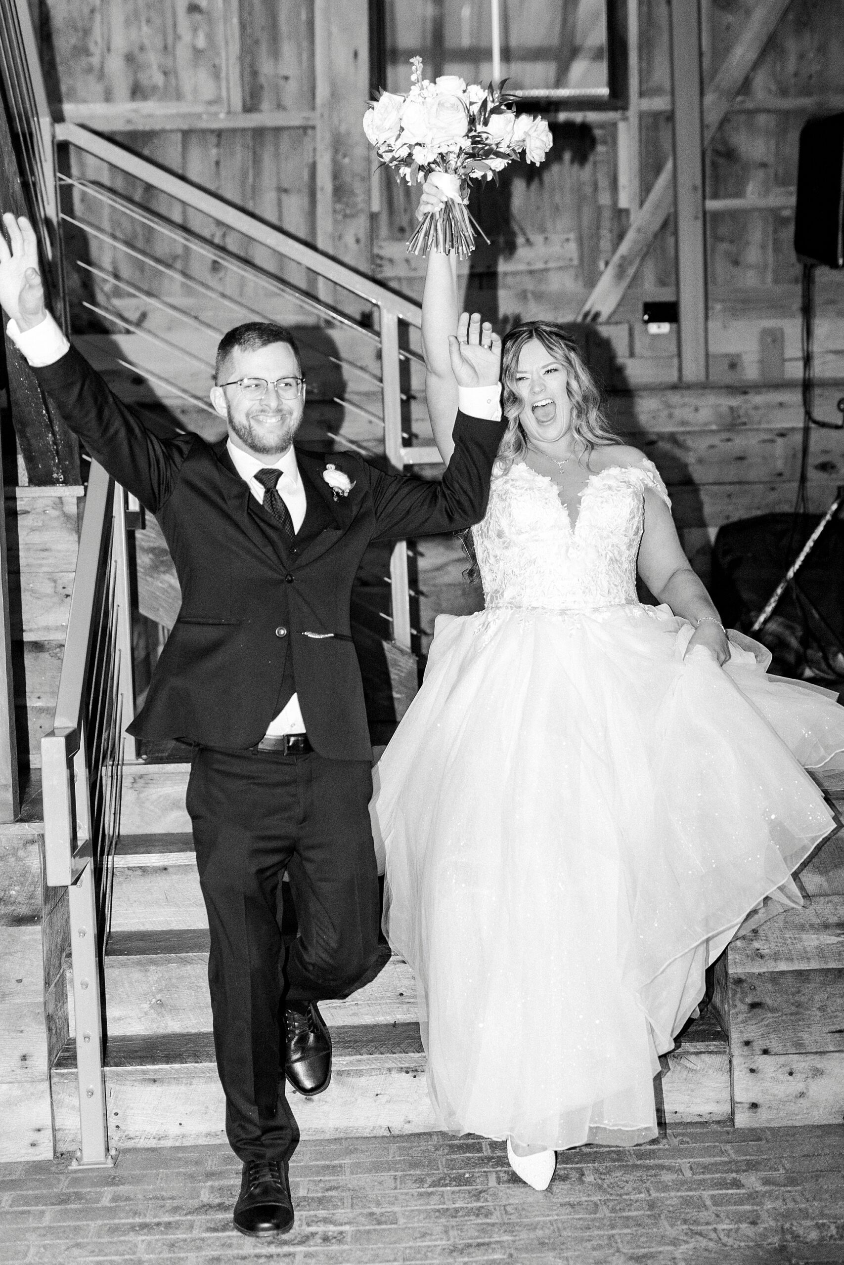 newlyweds cheer walking down stairs inside Summerfield Farms barn